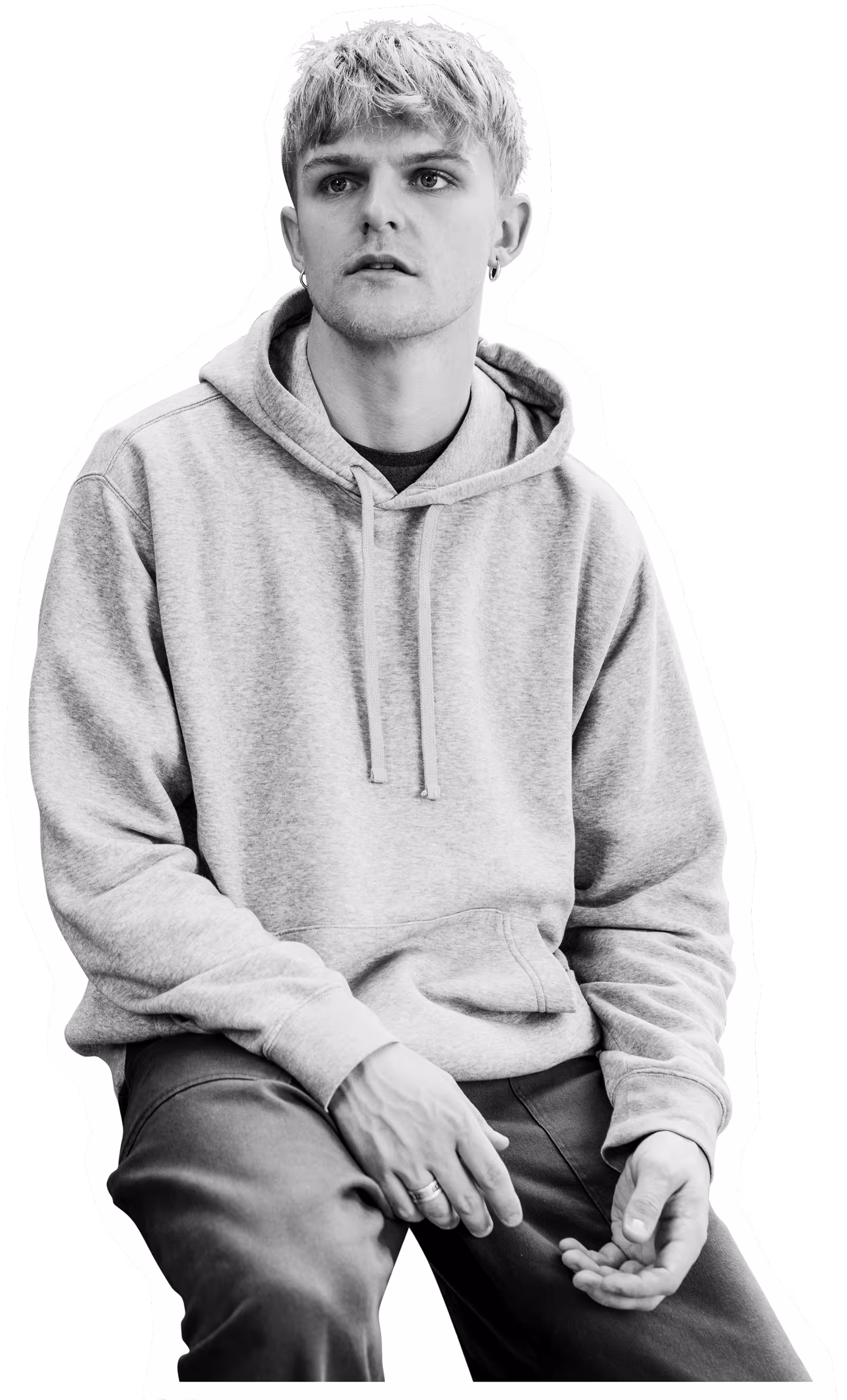 Young person in gray hoodie sitting with contemplative expression