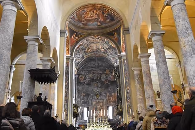 Veduta dell'altare e degli affreschi sovrastanti dalla navata centrale di una chiesa