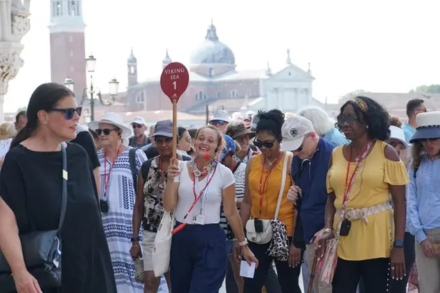 Un gruppo di persone segue una guida turistica che tiene una paletta rossa alzata per farsi riconoscere
