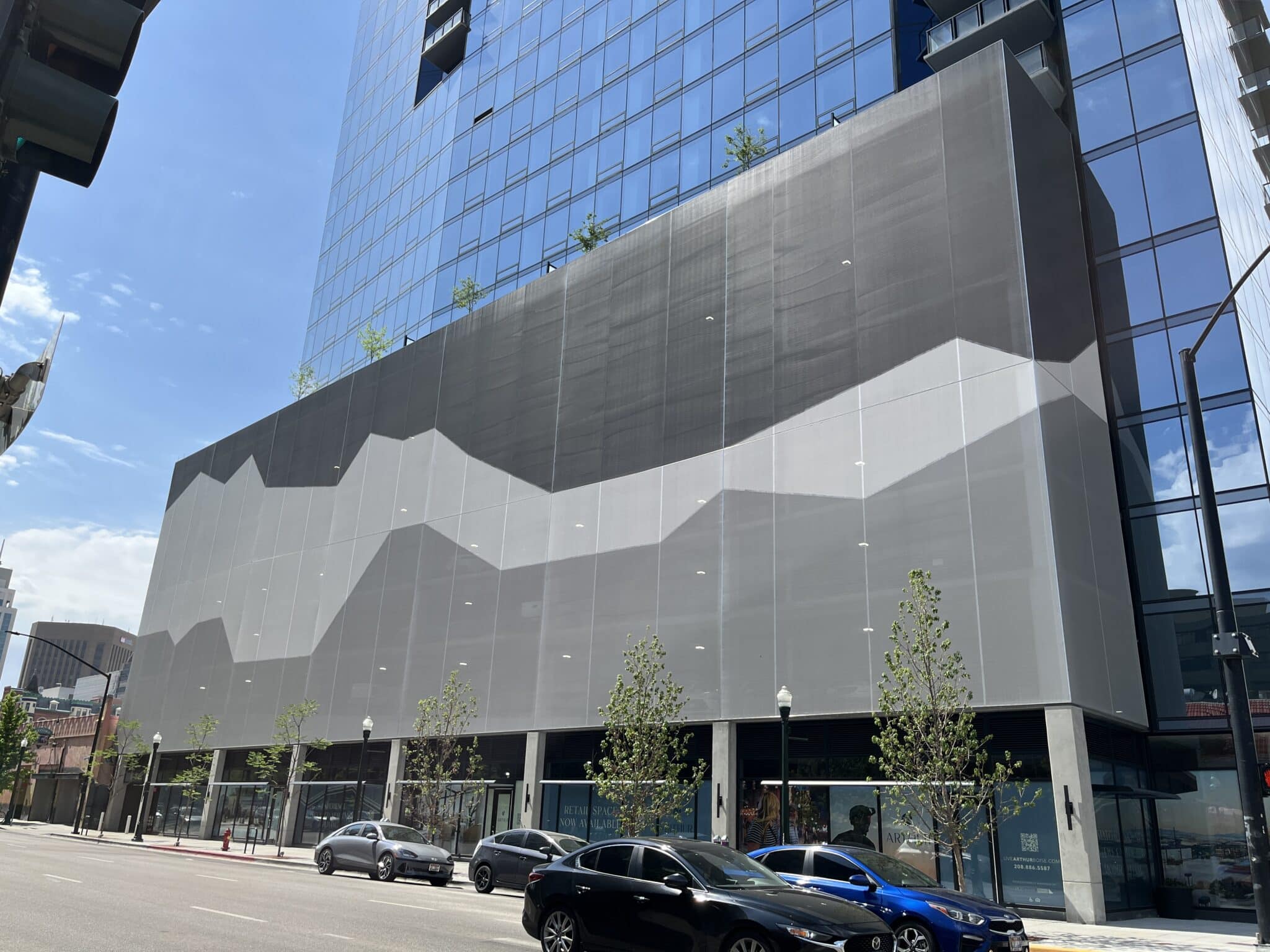 A black and white tensile facade sat on the side of a building. The imagery is an abstract portrayal of the mountains.