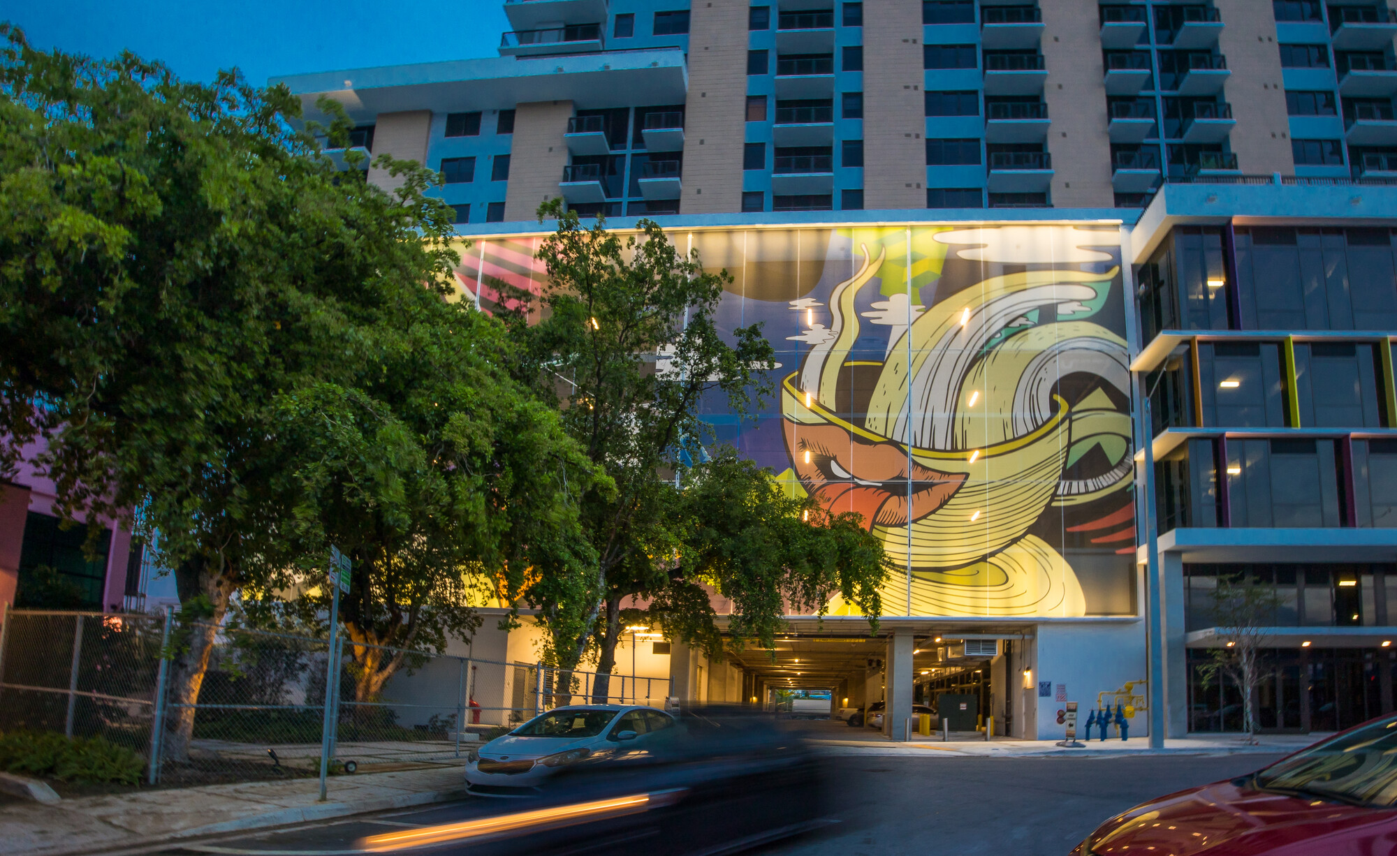 A graffiti-inspired tensile facade supported by a structural steel framework, peeking through some trees..‍