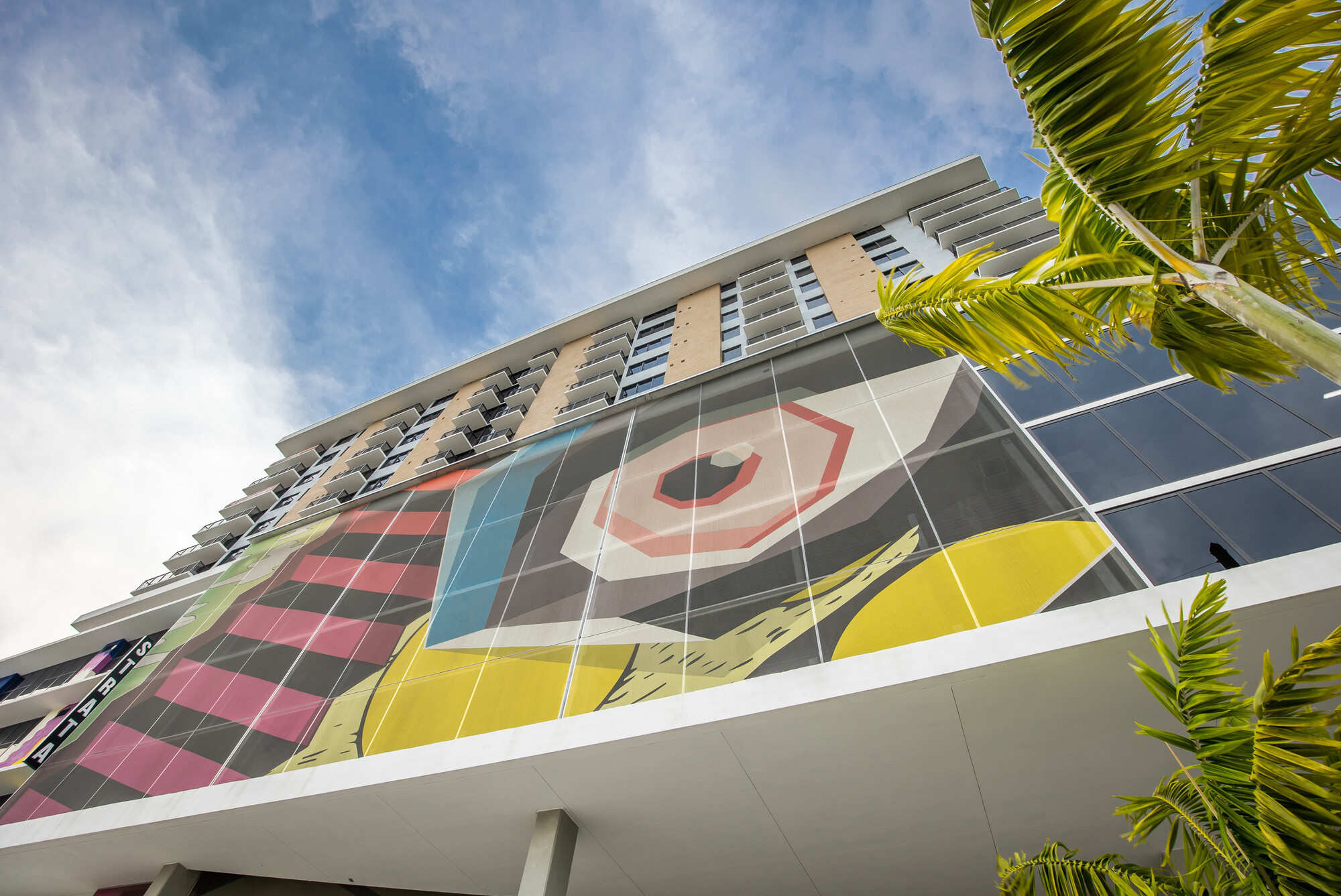 A sidewalk view of a different graphic facade that features organic shapes and a large eye.