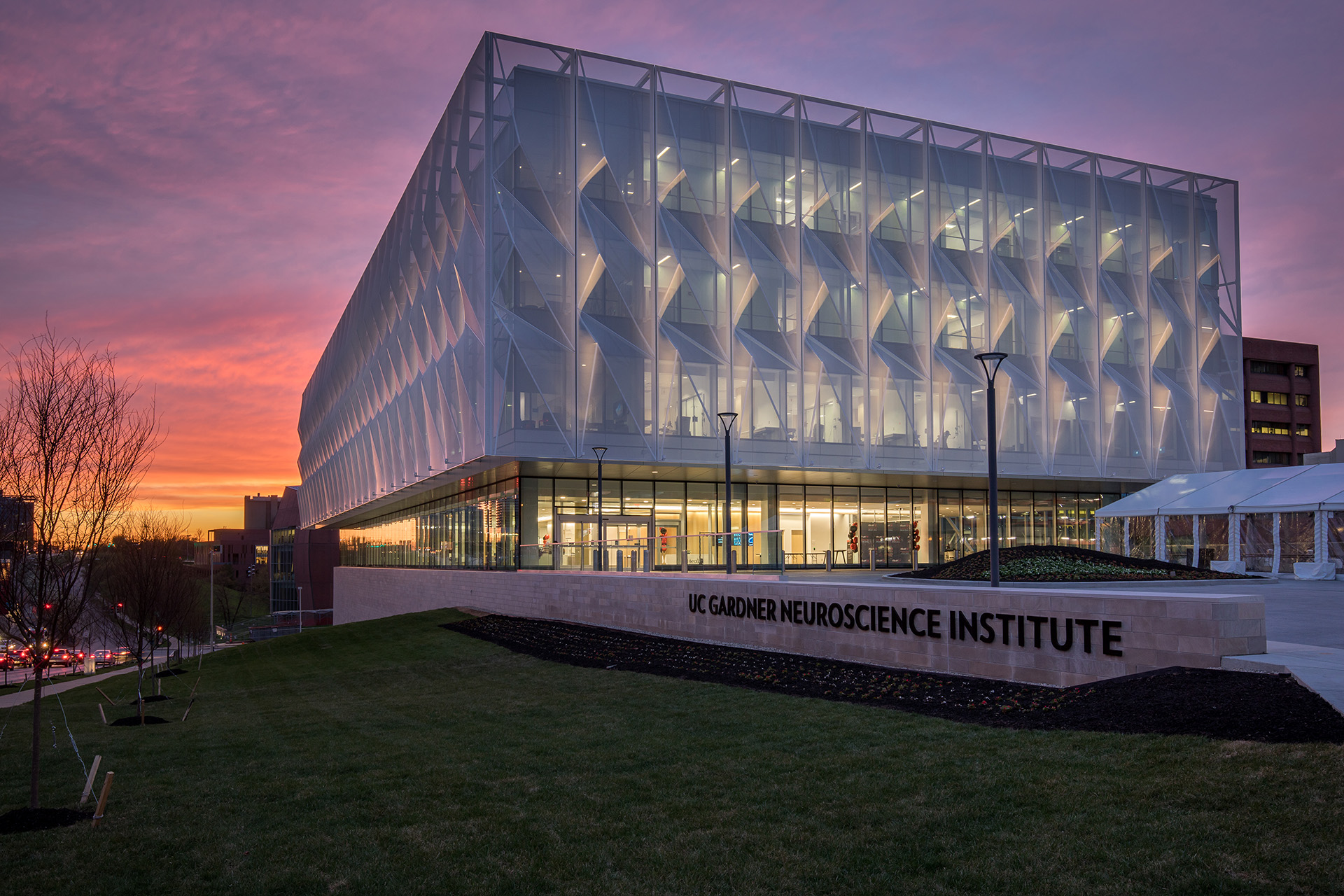 A 3D Cladding screen on steel facade that sits on a glass building. The image was taken at sunset which allows the viewers to see how the light from inside of the structure shines through.