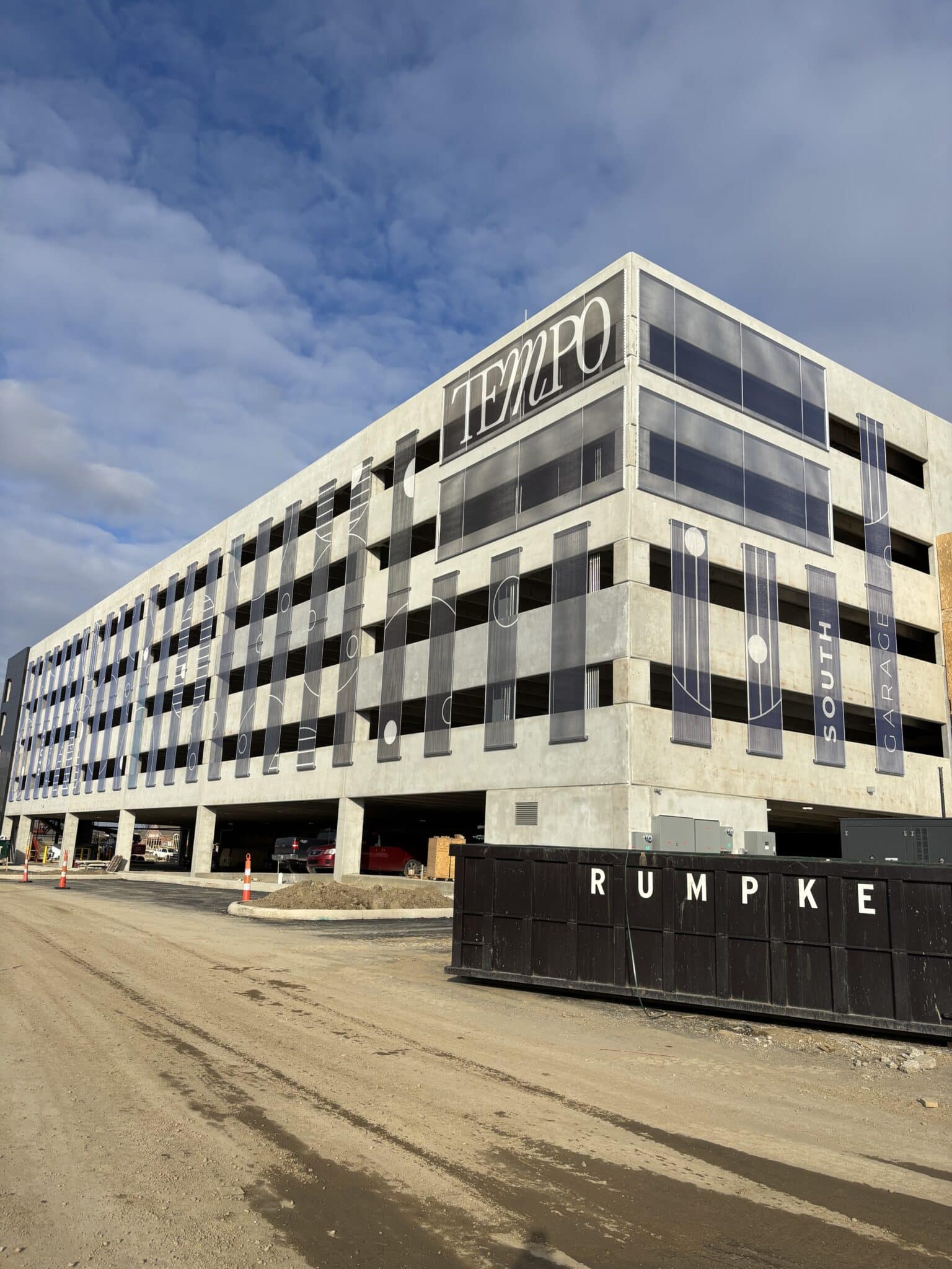 An array of paneled graphic facades that feature circular patterns and company branding printed onto the tensile mesh.