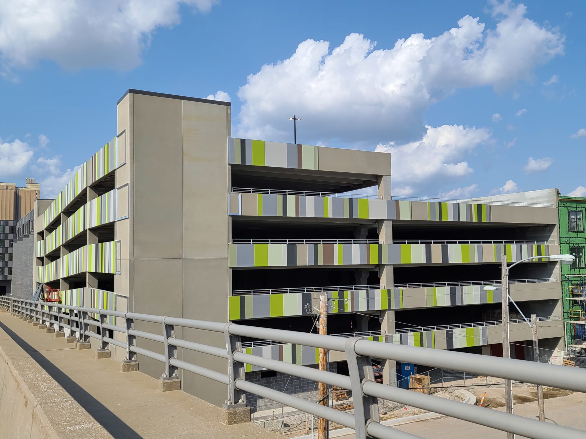 A lime green, white, grey, and black slotted facade sat on the concrete part of a parking garage.