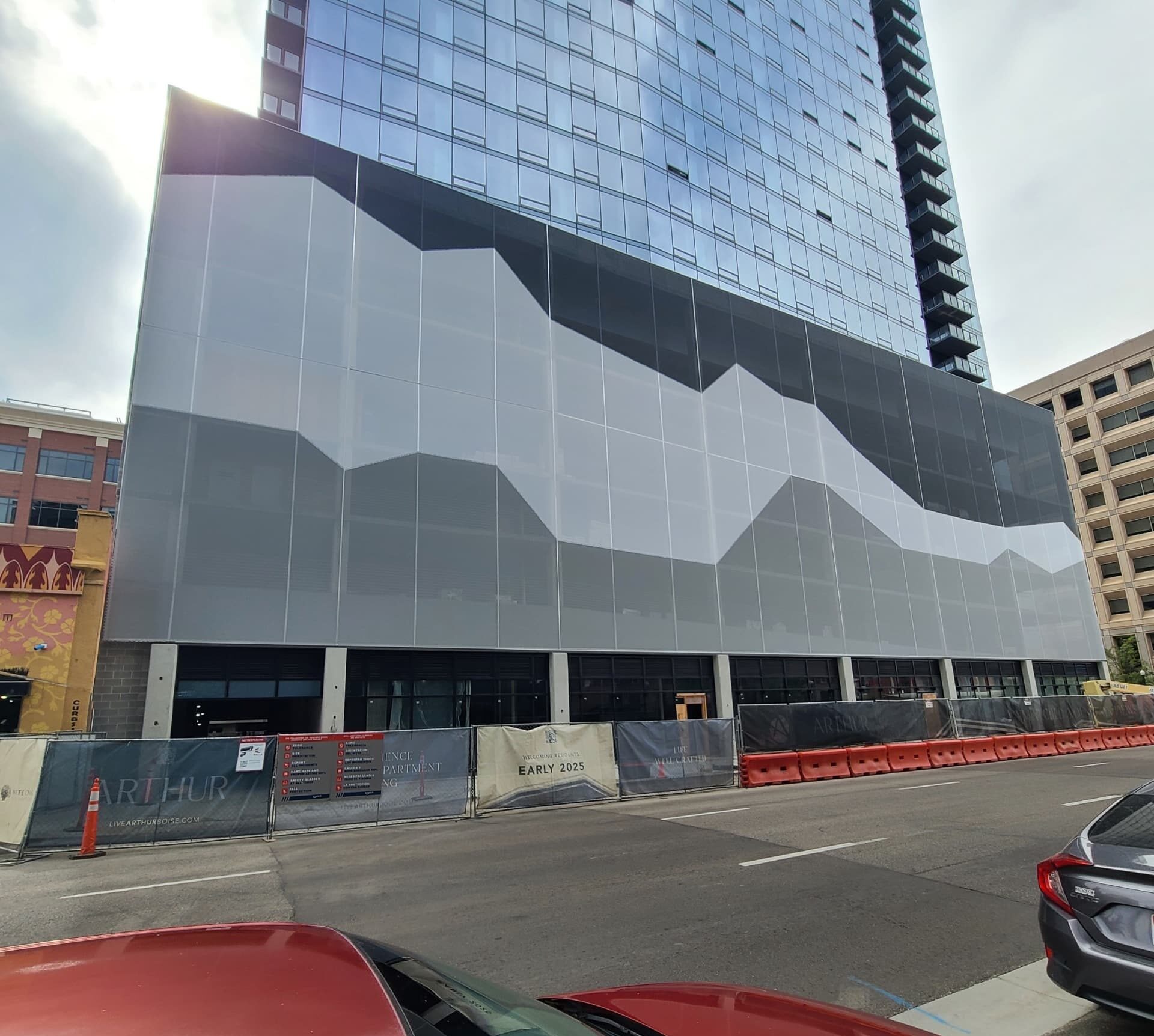 A black and white tensile facade sat on the side of a building. The imagery is an abstract portrayal of the mountains.