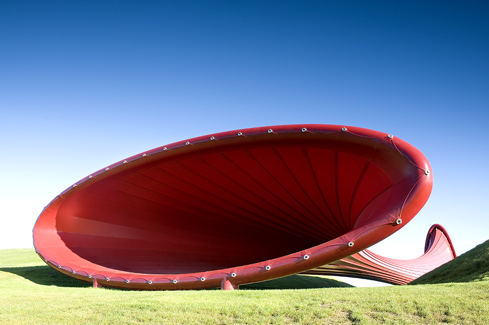 An image of the backside of the sculpture revealing that its an ovular cone shape. One side lays horizontal, the other side sits vertically.