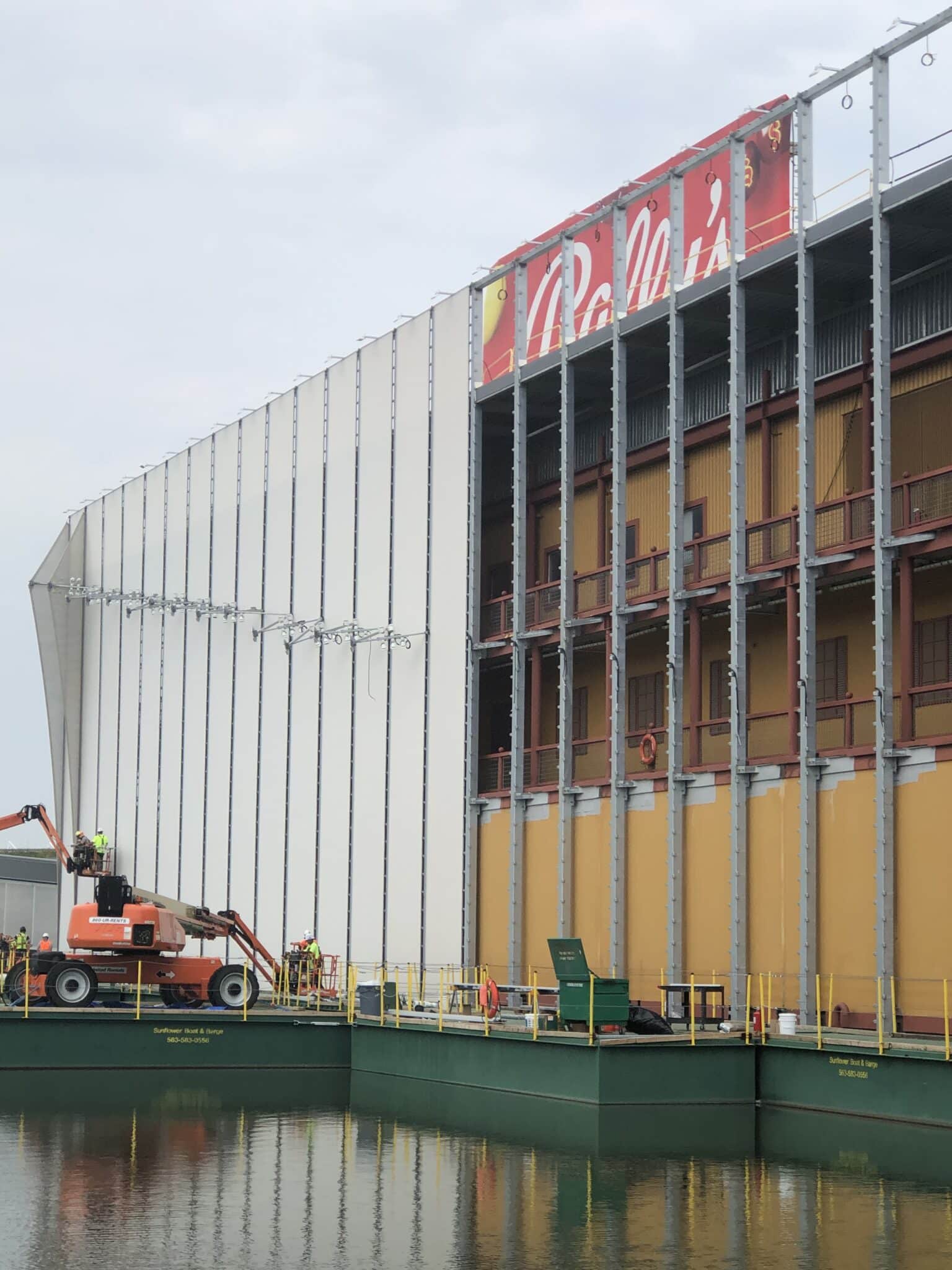 Process photos of the facade being installed over the original riverboat exterior.