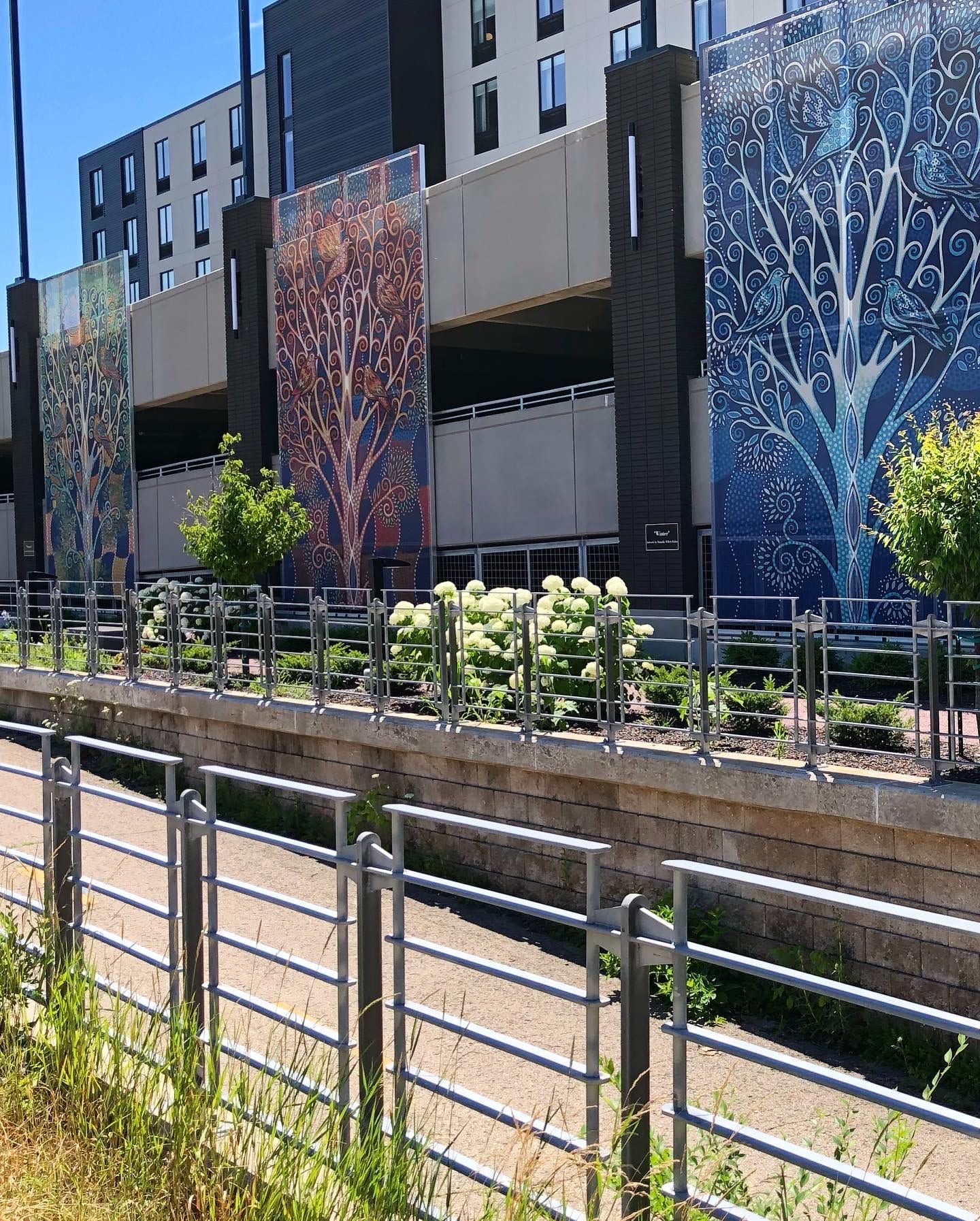 A view of the facades from the road, showing them behind the foliage.