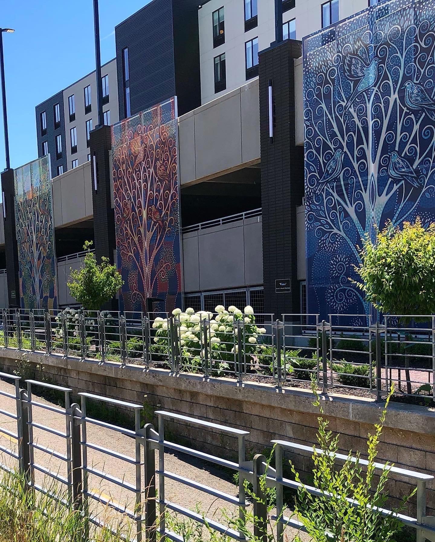 A view of the facades from the road, showing them behind the foliage.