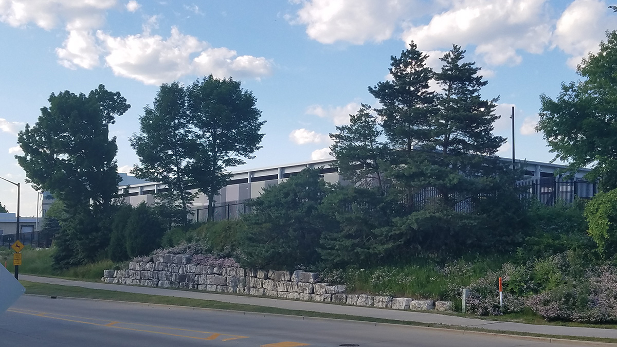 A view of the facade hiding behind some trees as seen from the street.