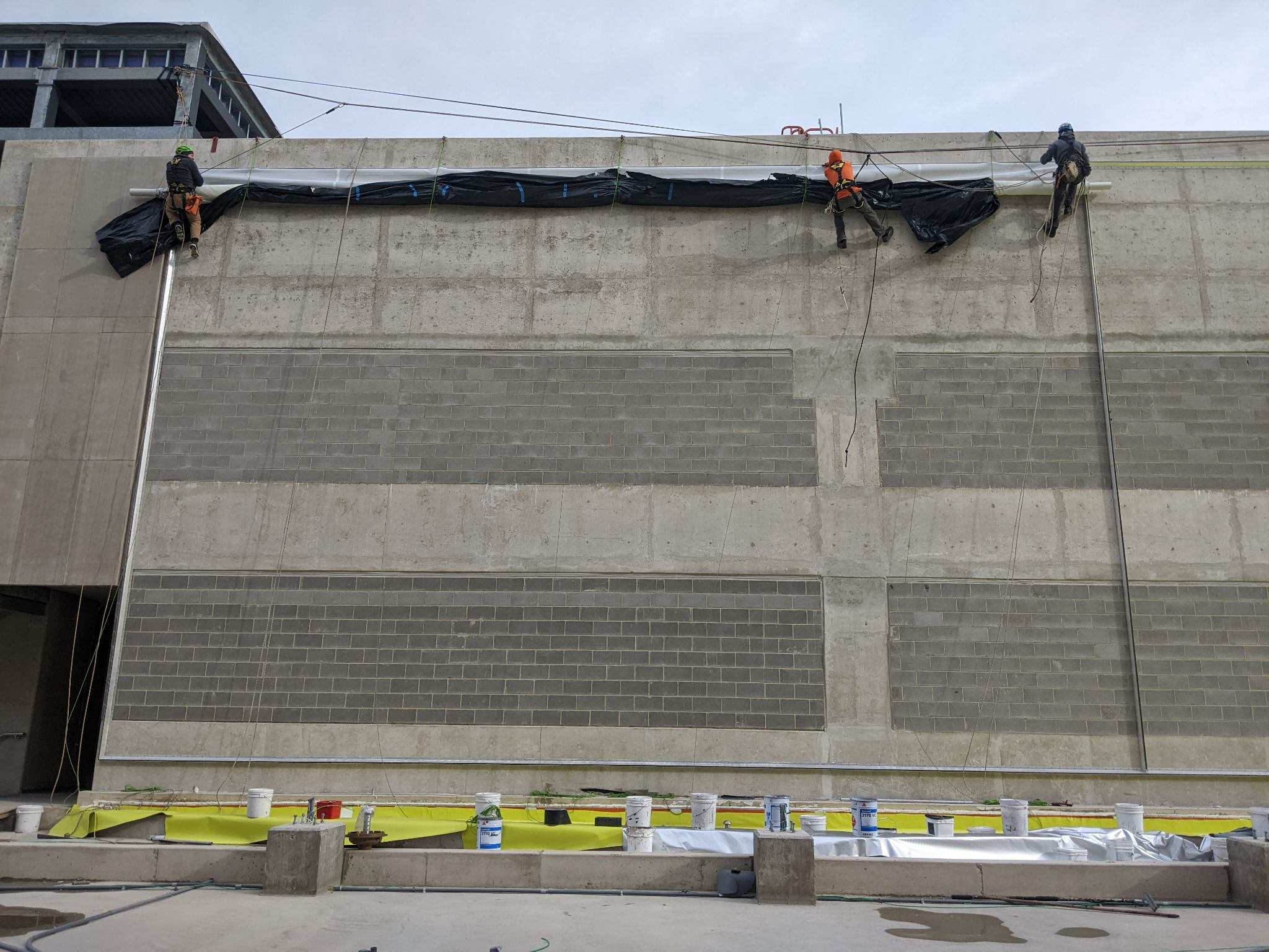 Process photo of the flat white facade being installed on a steel cladding frame.