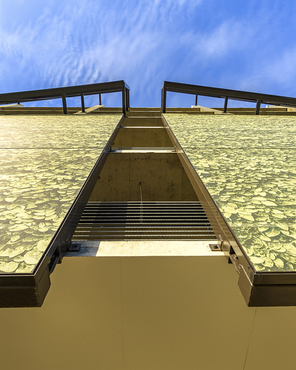 A view from the sidewalk looking up through the space where two facades meet.