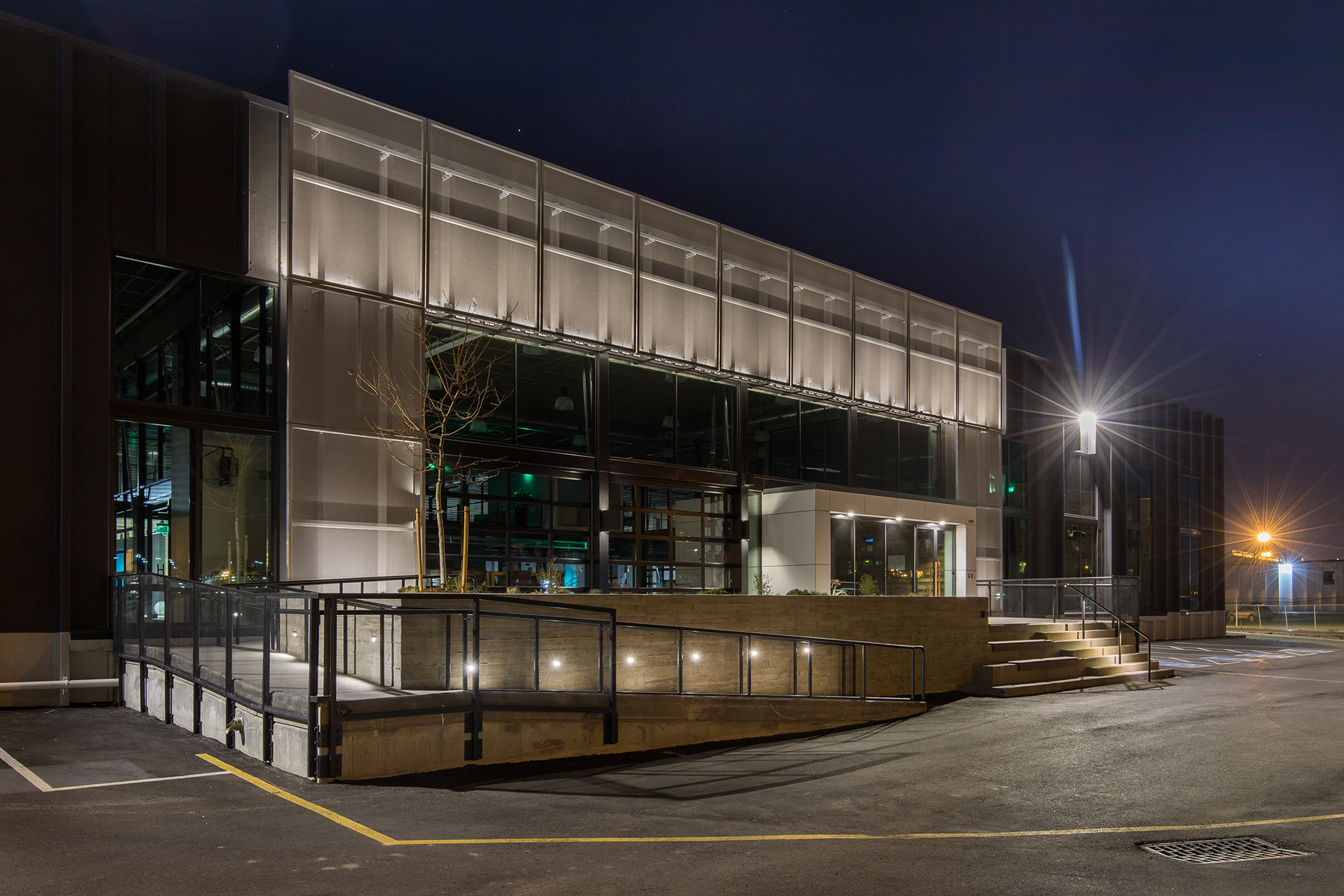 12 grey coated PES mesh facade panels that stretch over the entrance of a building.