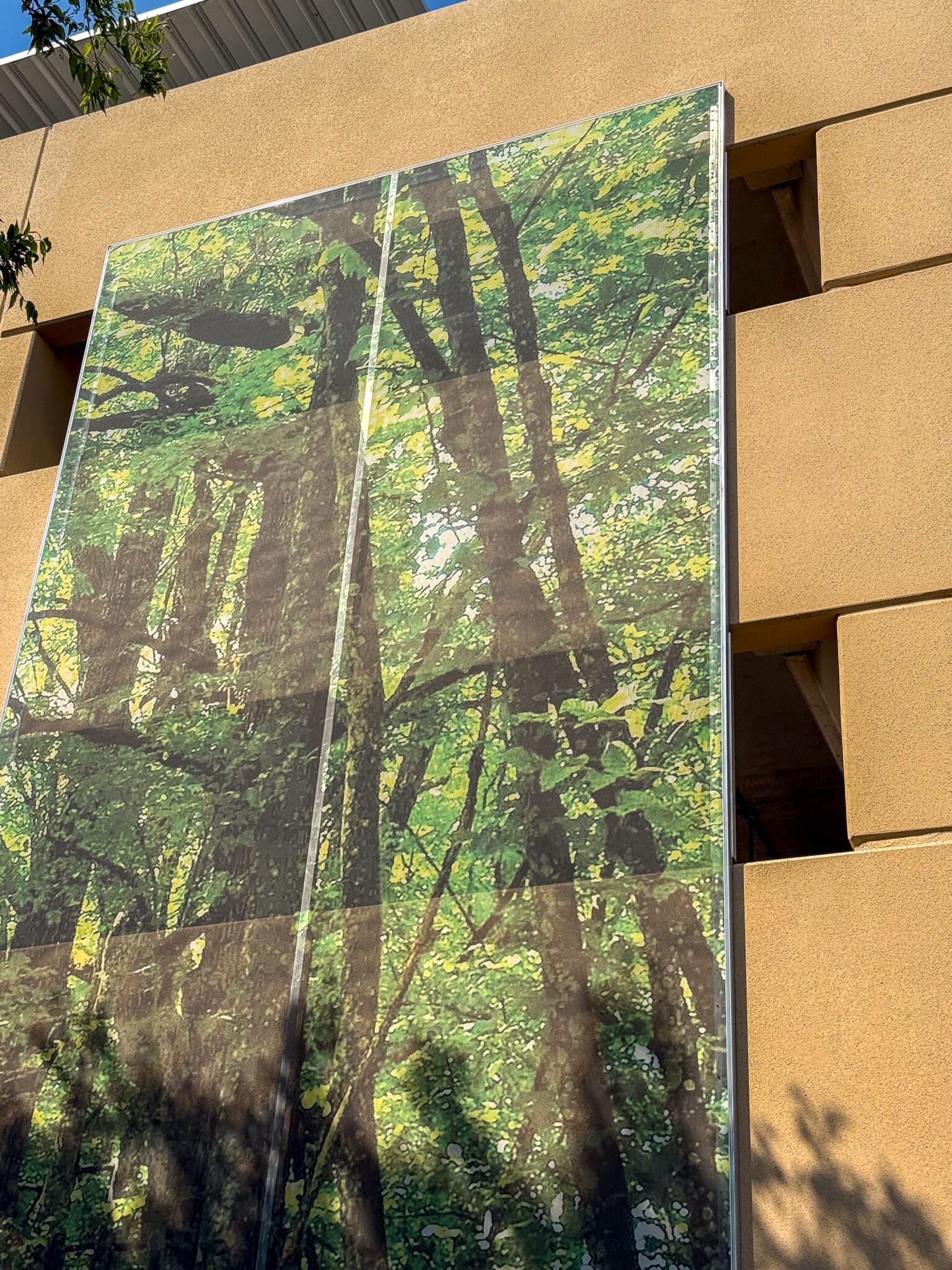 A three story printed facade that features imagery of a forrest.