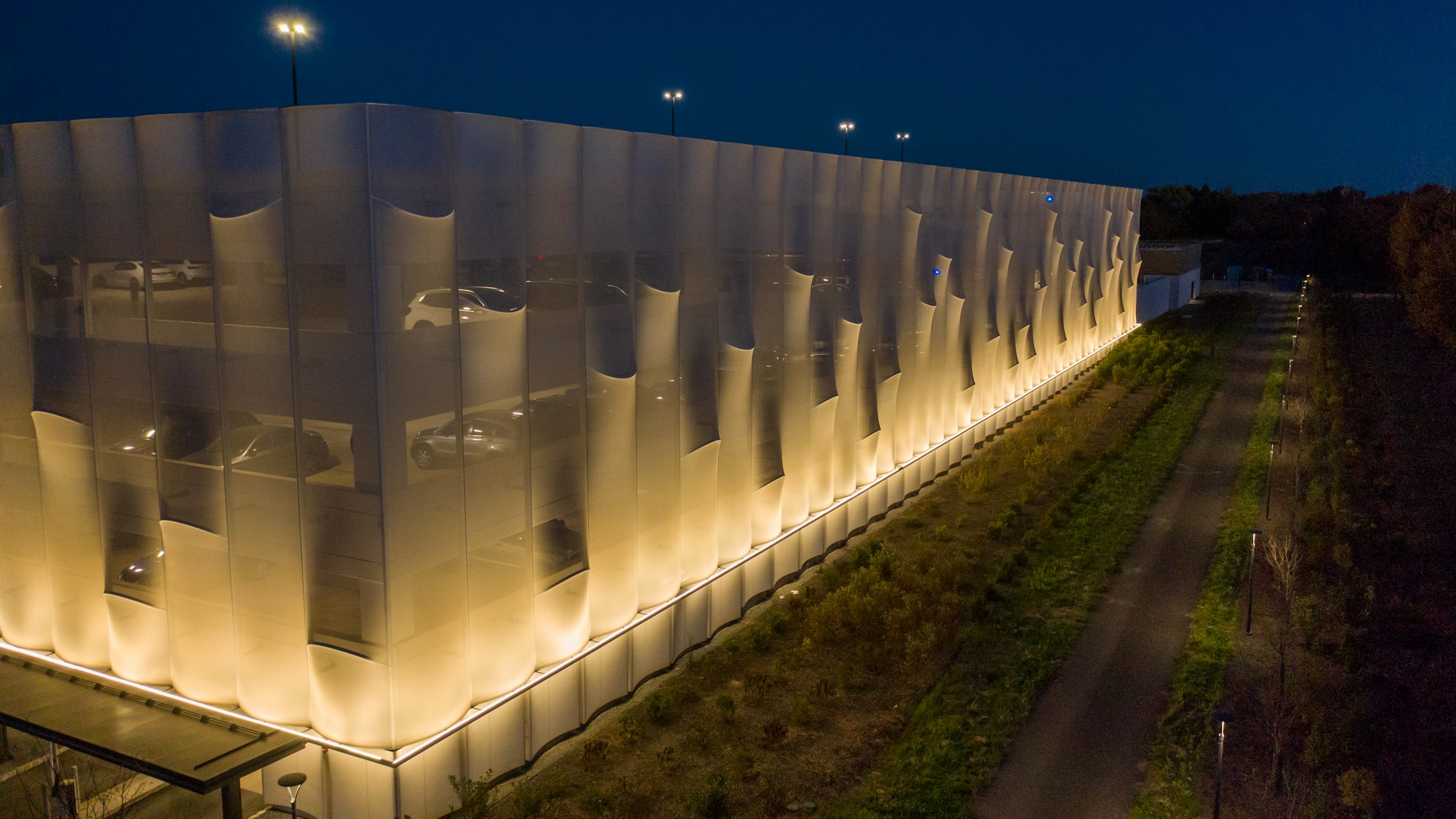 An opaque PTFE ventilated fiberglass mesh with semi-circled curved rods that stick out, creating a three dimensional surface on the facade.