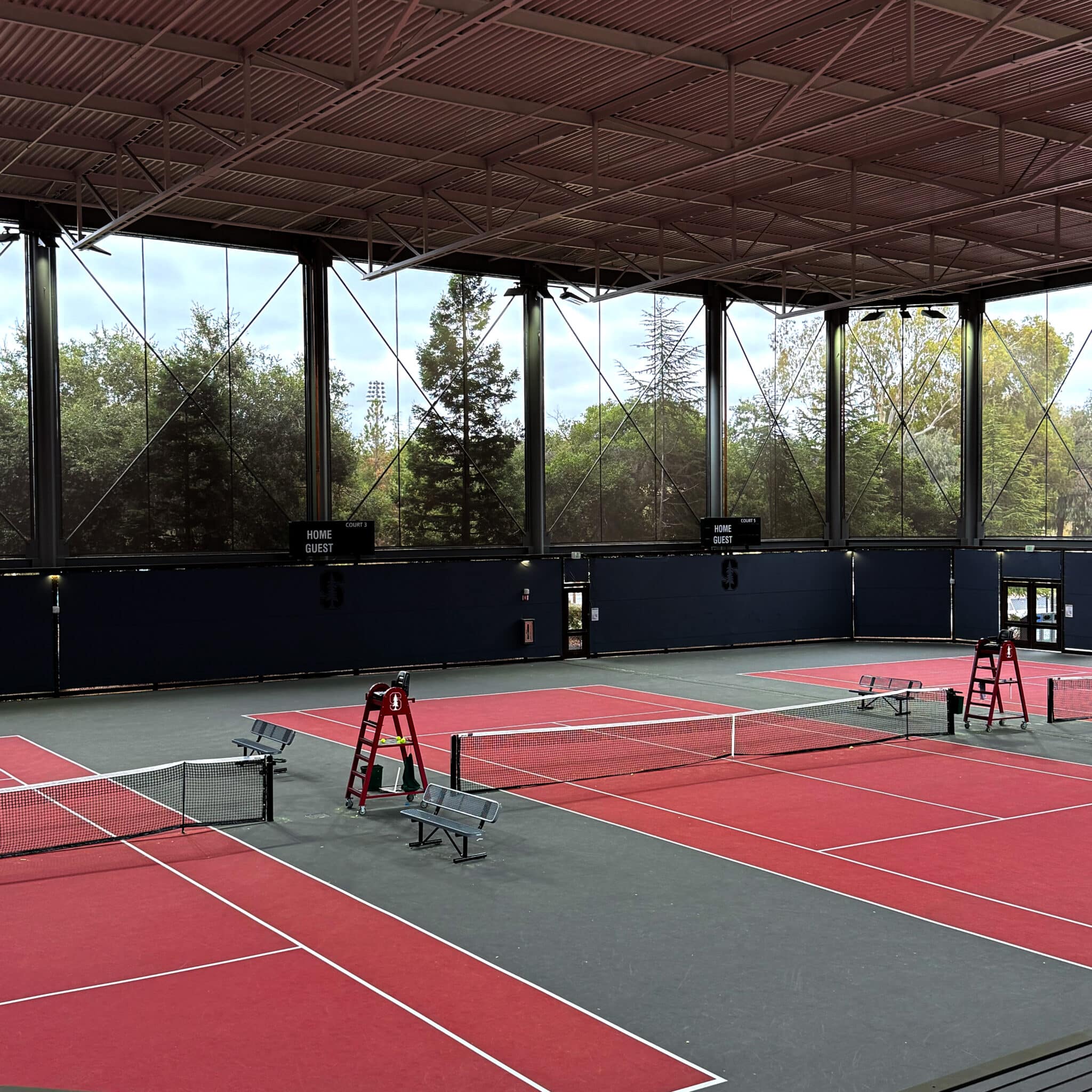 Three tennis courts in a covered structure with walls made of see through facades allowing the players to still feel like they are practicing outside.