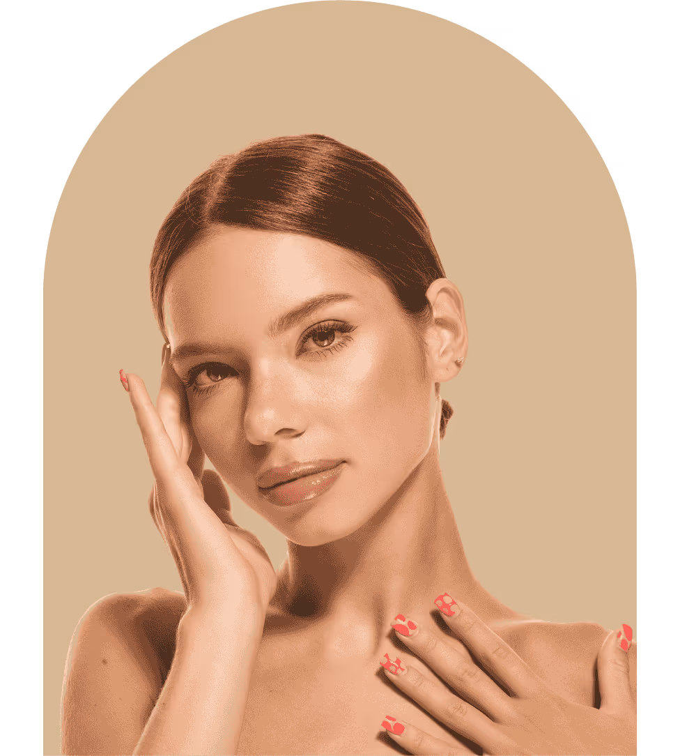 Portrait of a woman with smooth skin and glossy lips touching her face and chest, with pink nail polish on her nails.