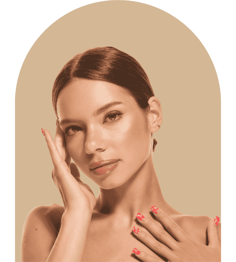 Portrait of a woman with smooth skin and glossy lips touching her face and chest, with pink nail polish on her nails.