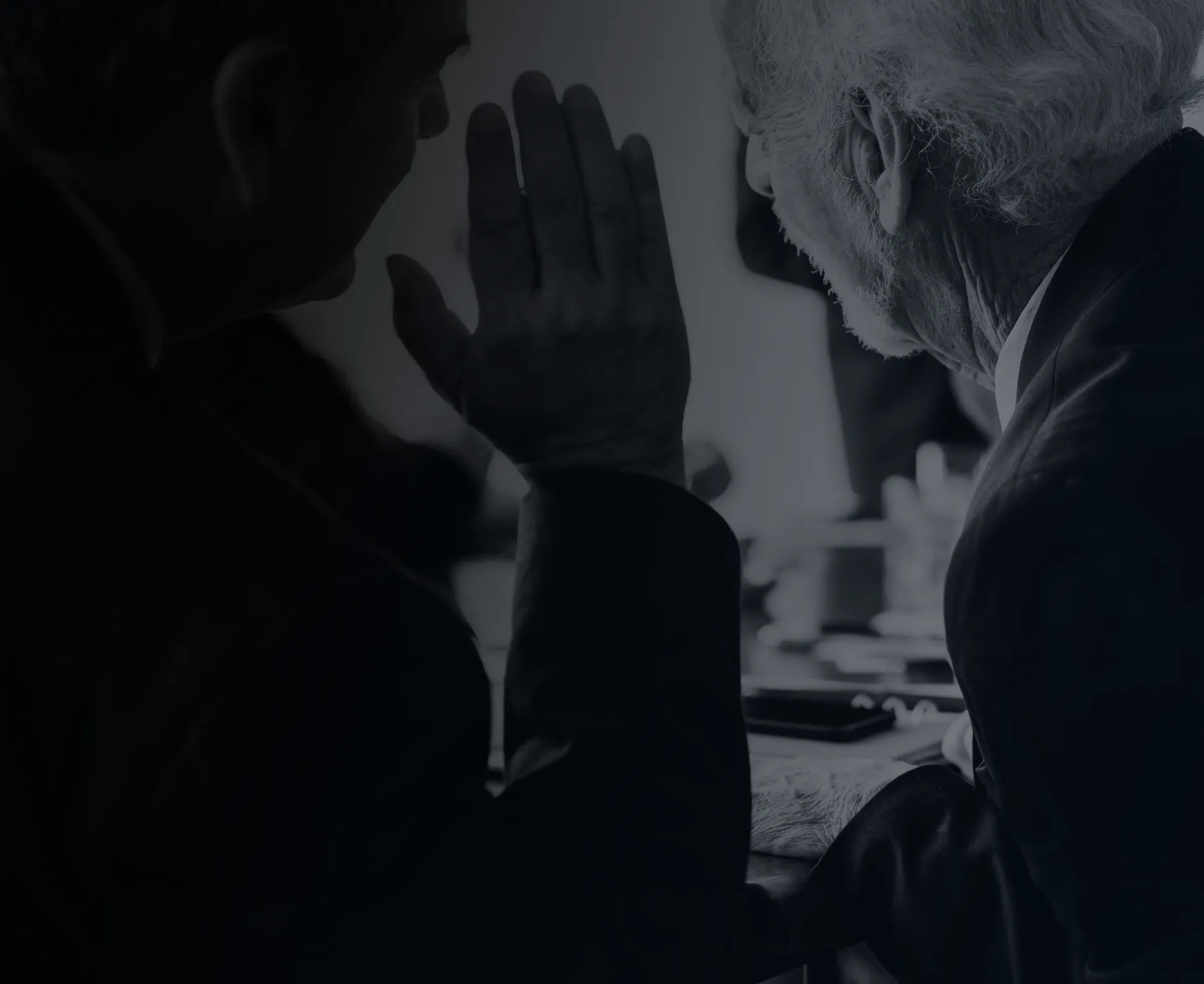 man with hand up whispering to another man