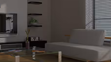 Modern living room with gray sofa, wall-mounted TV, and window blinds.