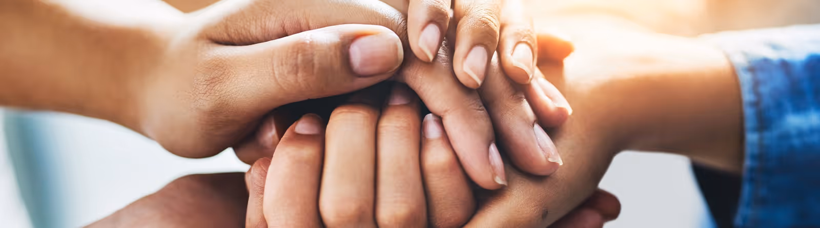 Close-up of several hands stacked together in a gesture of unity and support.