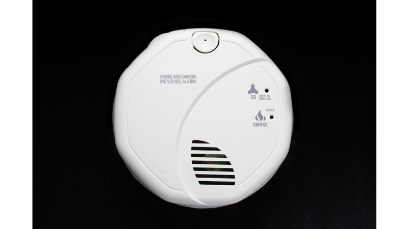 White smoke and carbon monoxide alarm with indicator lights and a test button on a black background.