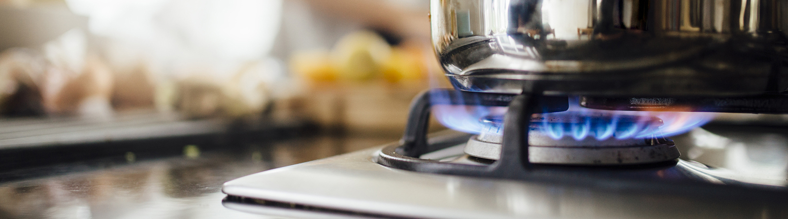 Close-up of a pot heating on a gas stove with a blue flame.