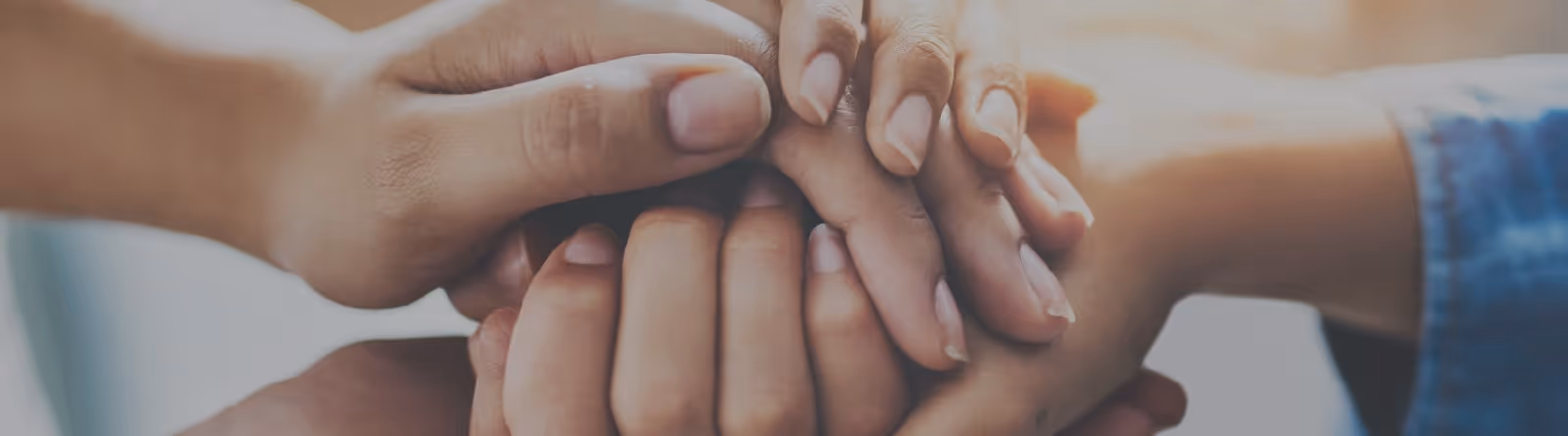 Multiple hands stacked together symbolizing unity and support.