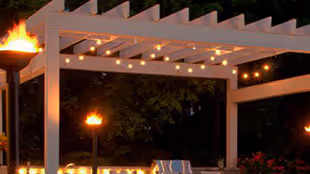 Outdoor patio with string lights and tiki torches lit at night.