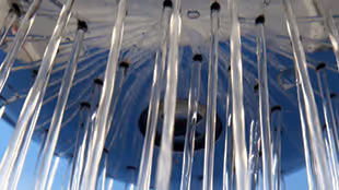 Close-up of multiple clear water streams flowing downward against a blue background.