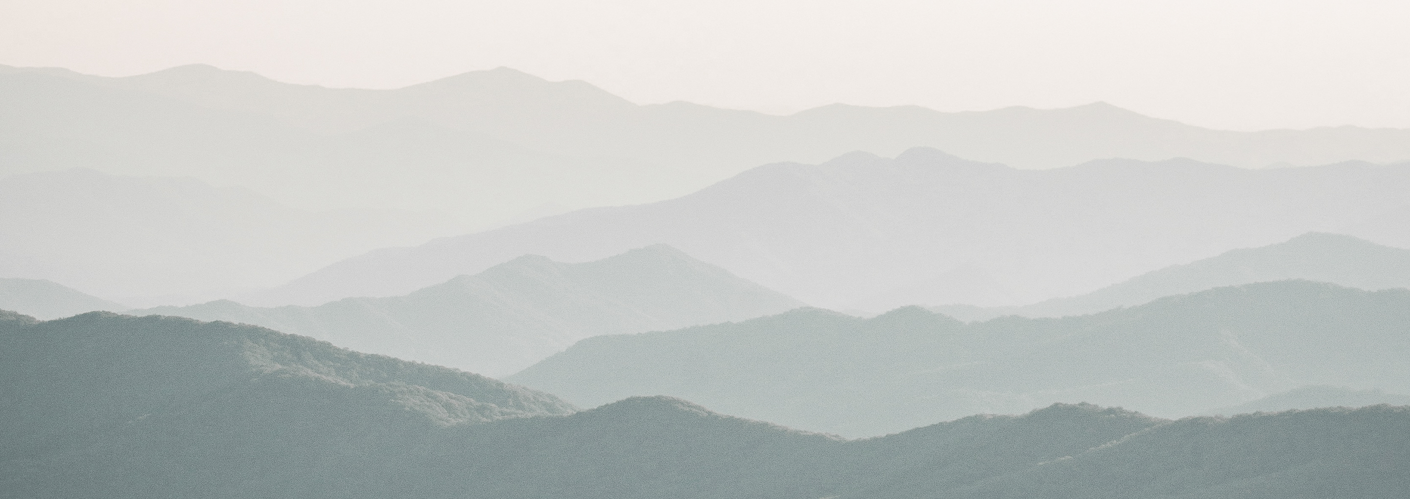 A mountain range in grayscale where the mountain tops fade out in the distance.