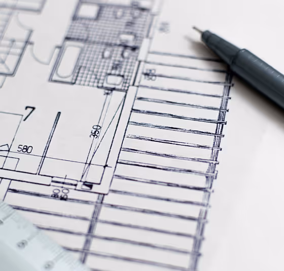 Close-up of architectural blueprint with ruler and pen on white paper.