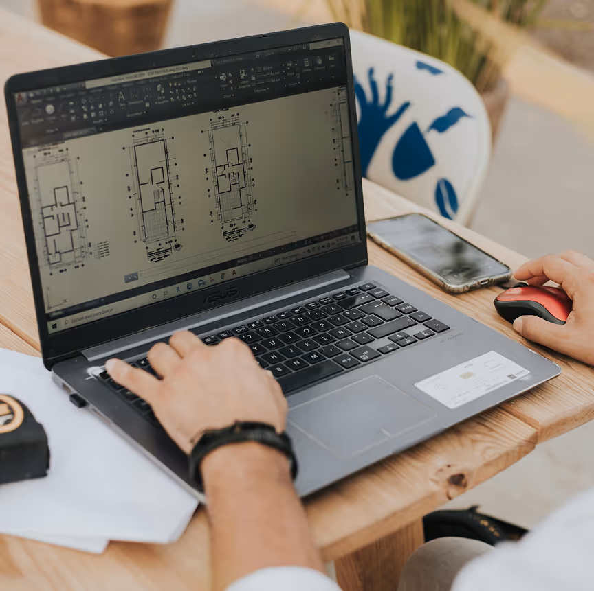 Person working on a laptop displaying architectural floor plans in a design software.