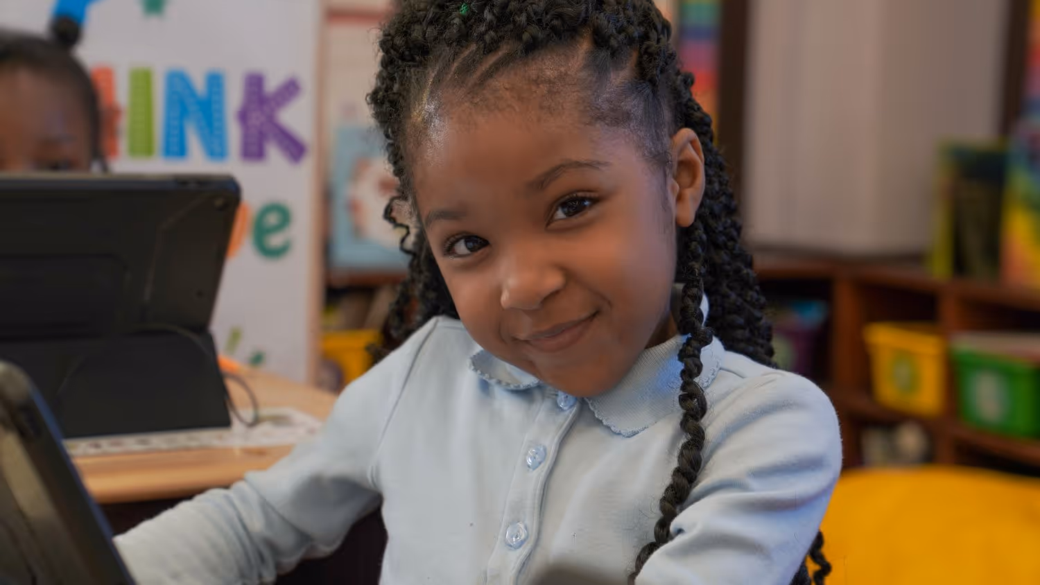 Student smiling while using a computer in a classroom.