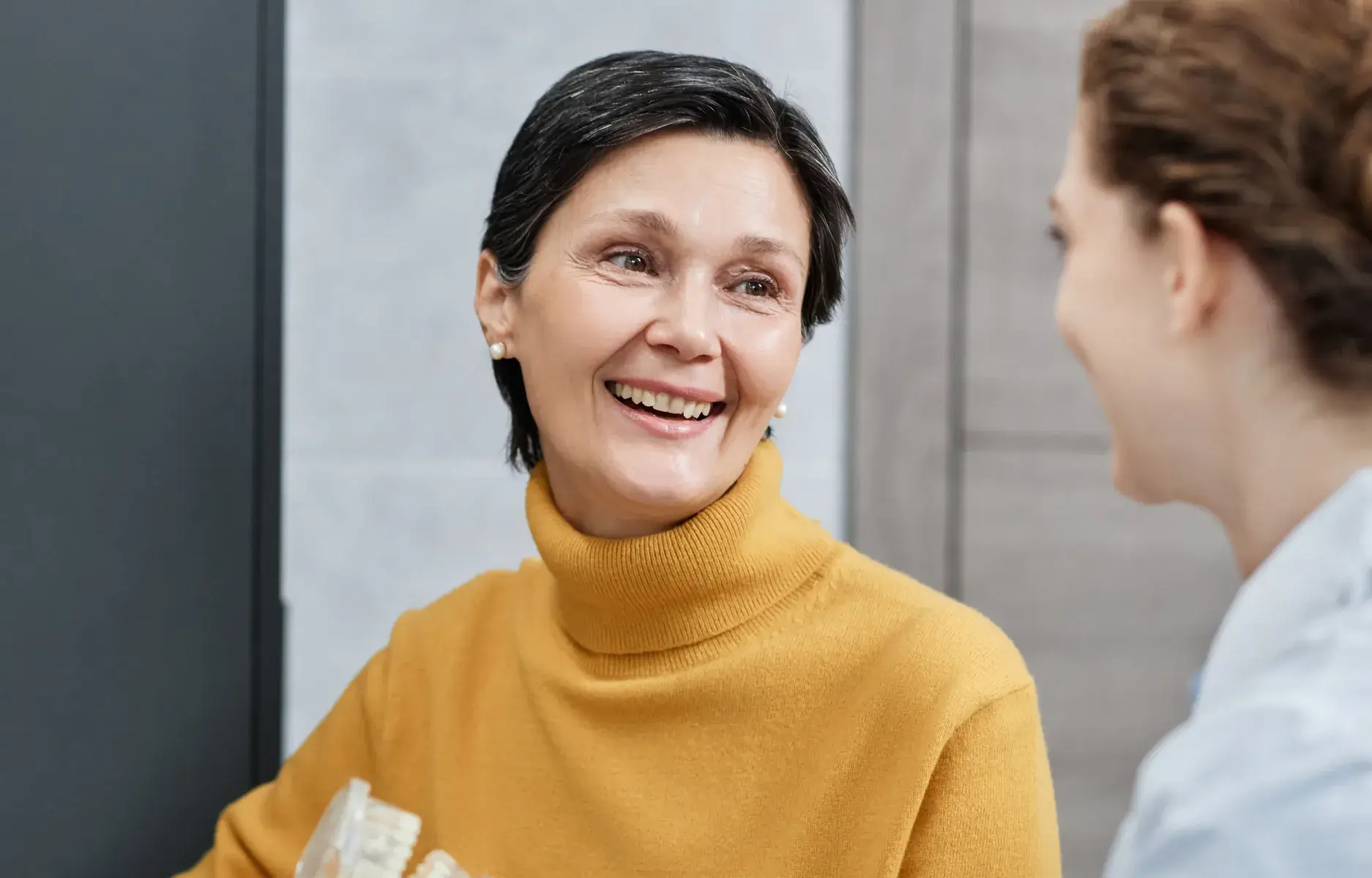 a woman in a yellow sweater is talking to another woman