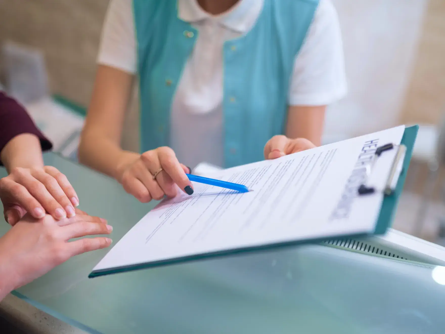 a person signing a document with a blue pen