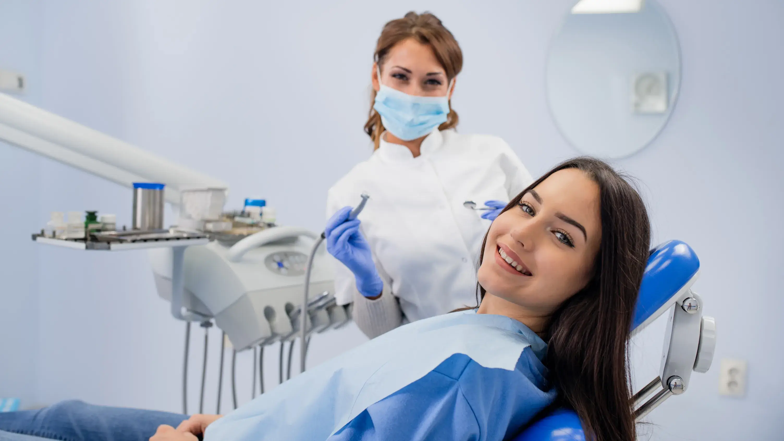 a woman sitting in a dentist chair with a mask on