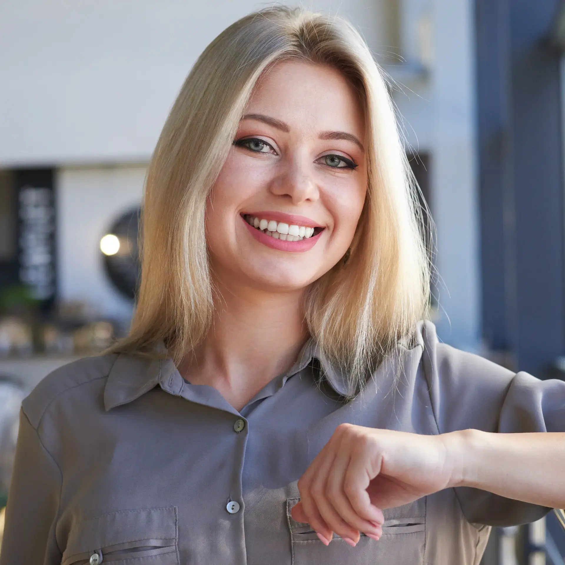 a woman with blonde hair smiling and pointing at the camera