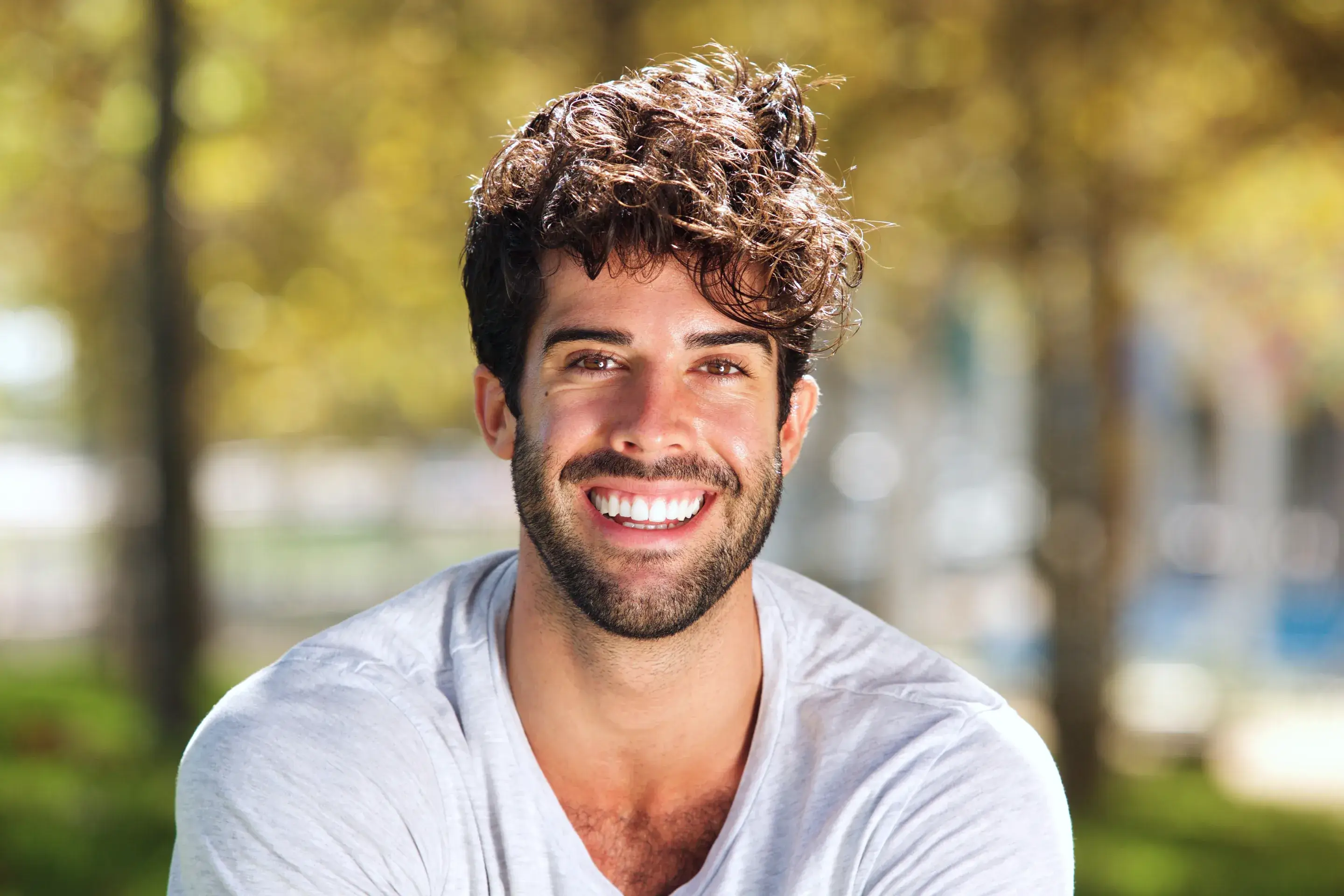 a man with curly hair smiling at the camera