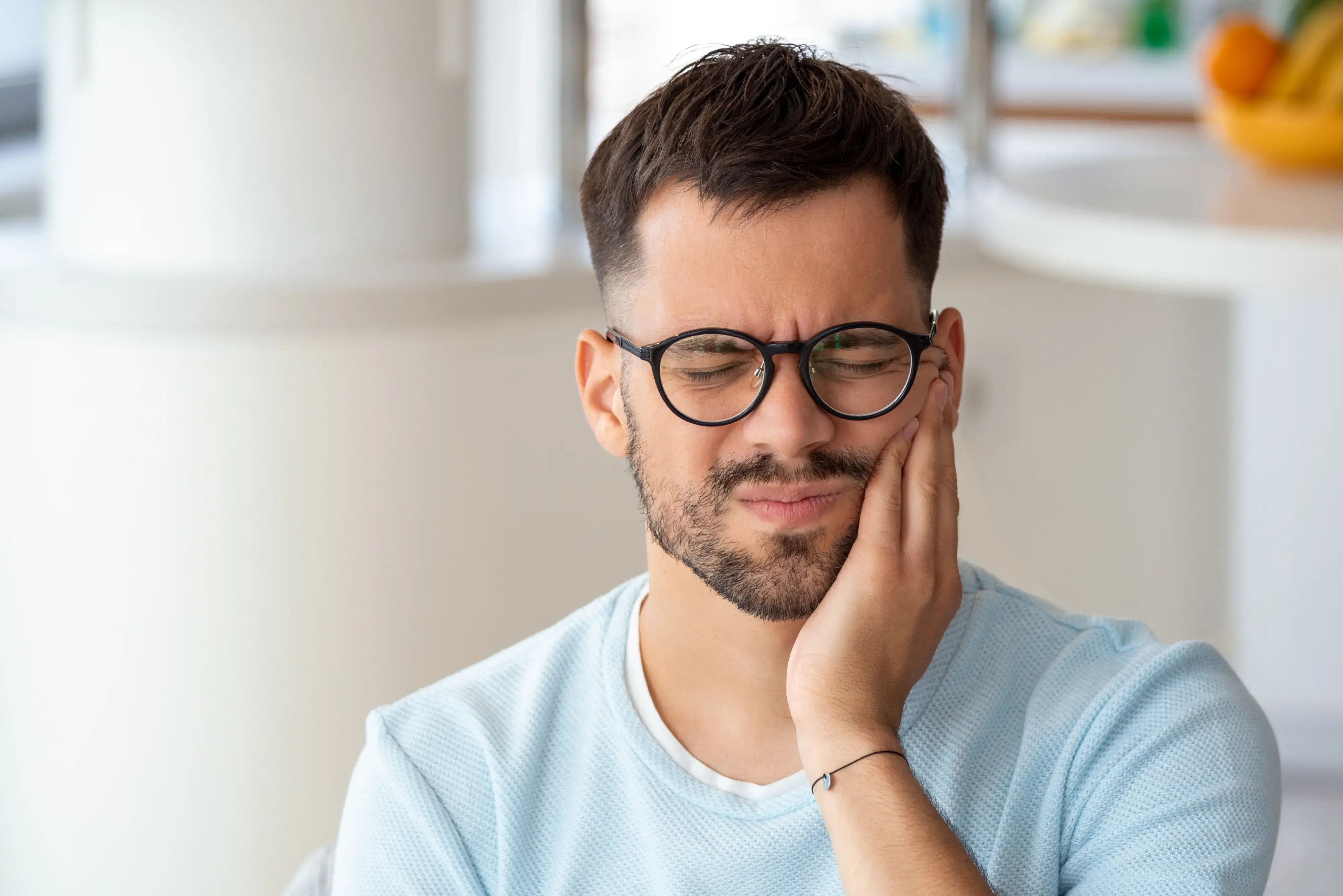 a man wearing glasses is holding his hand to his face
