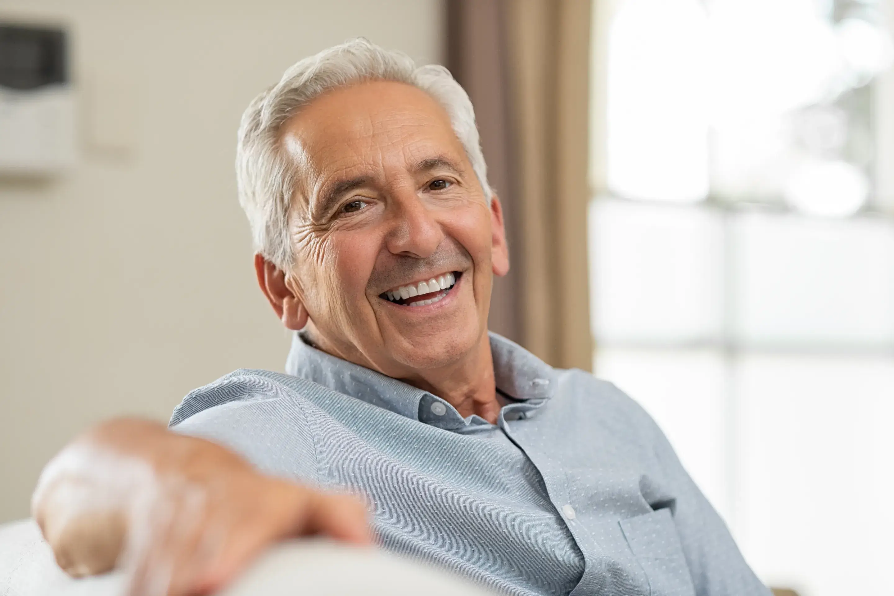 a man smiling while sitting on a couch