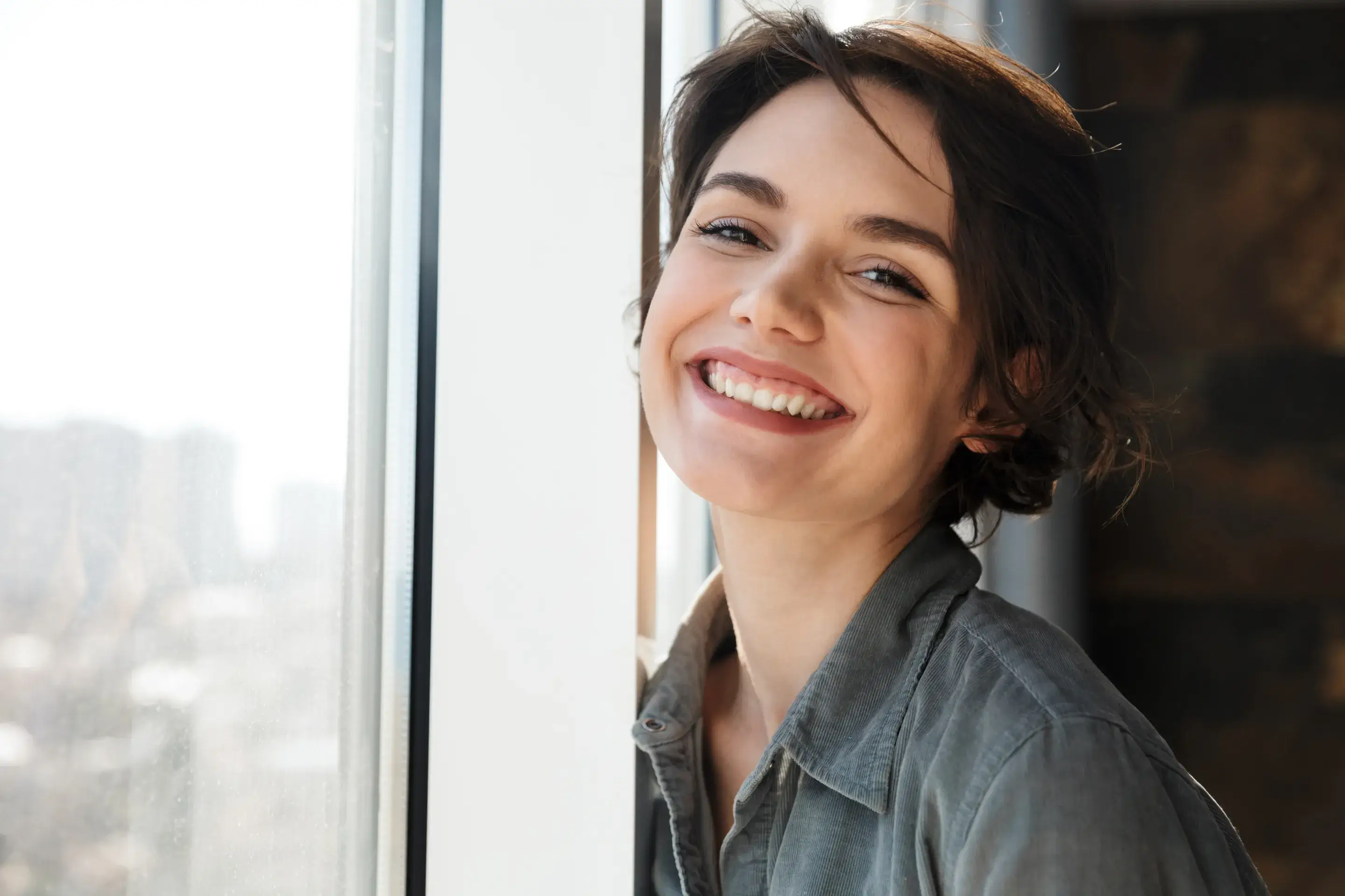 a woman is smiling while looking out a window