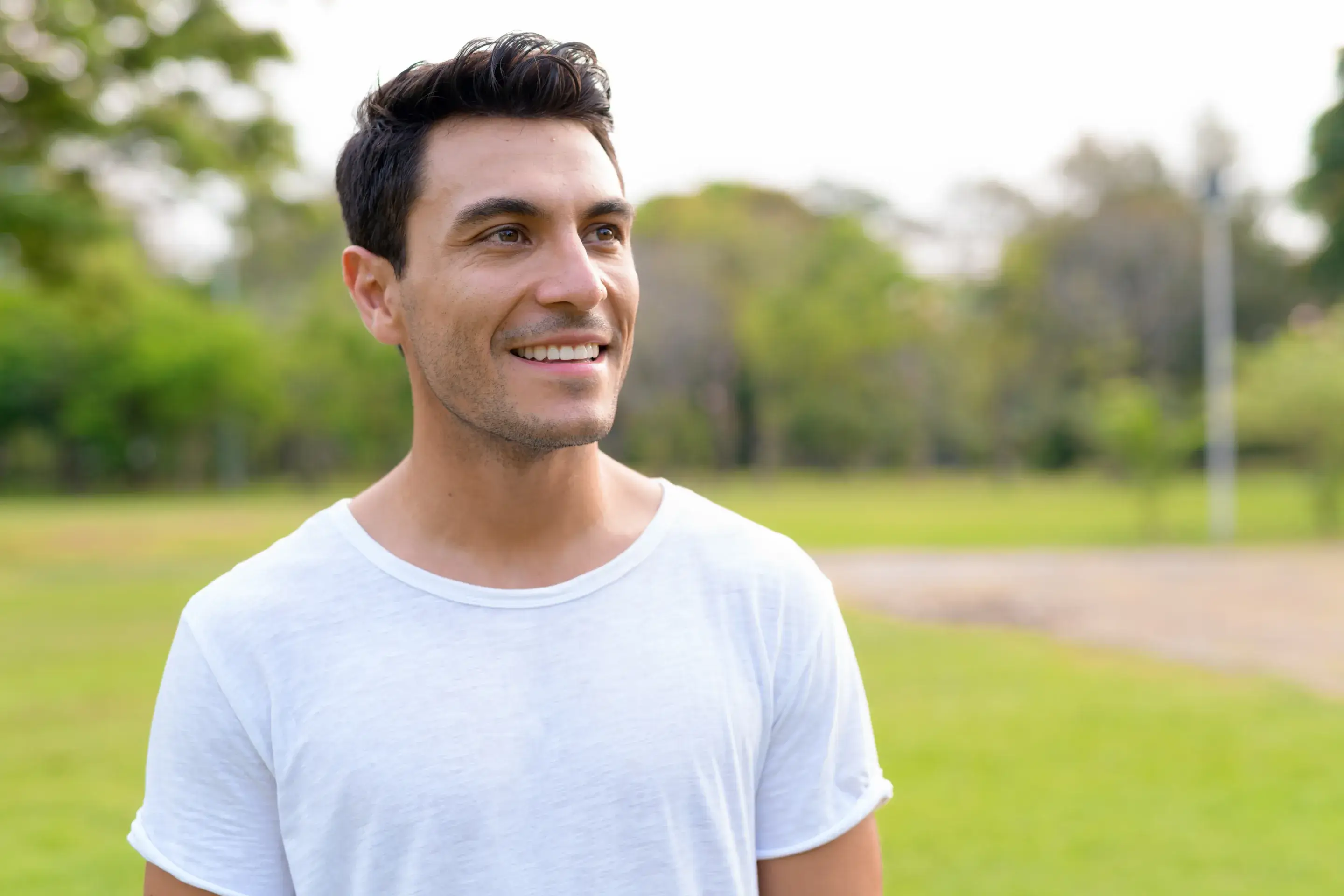 a man in a white shirt standing in a park