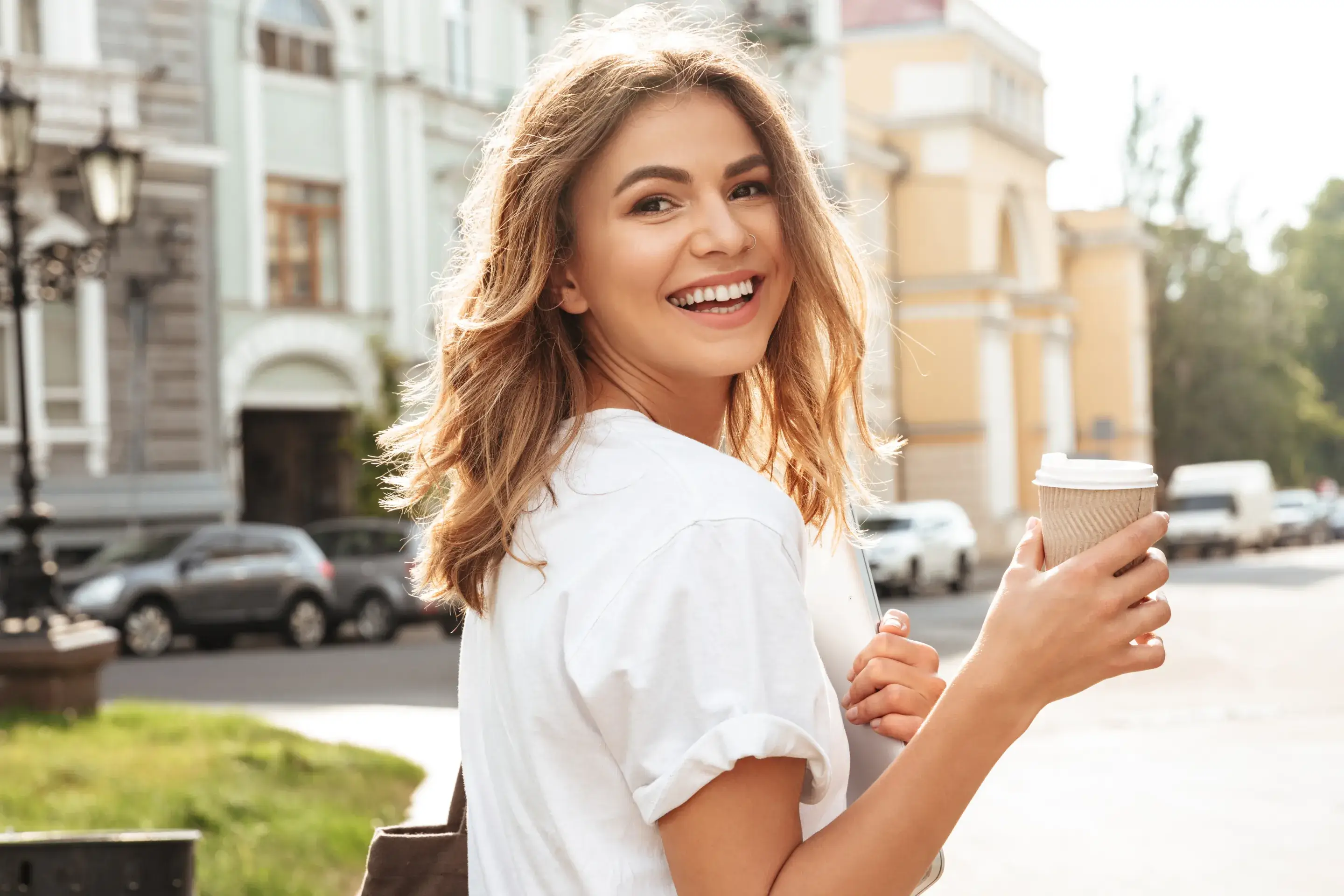 a smiling woman holding a cup of coffee