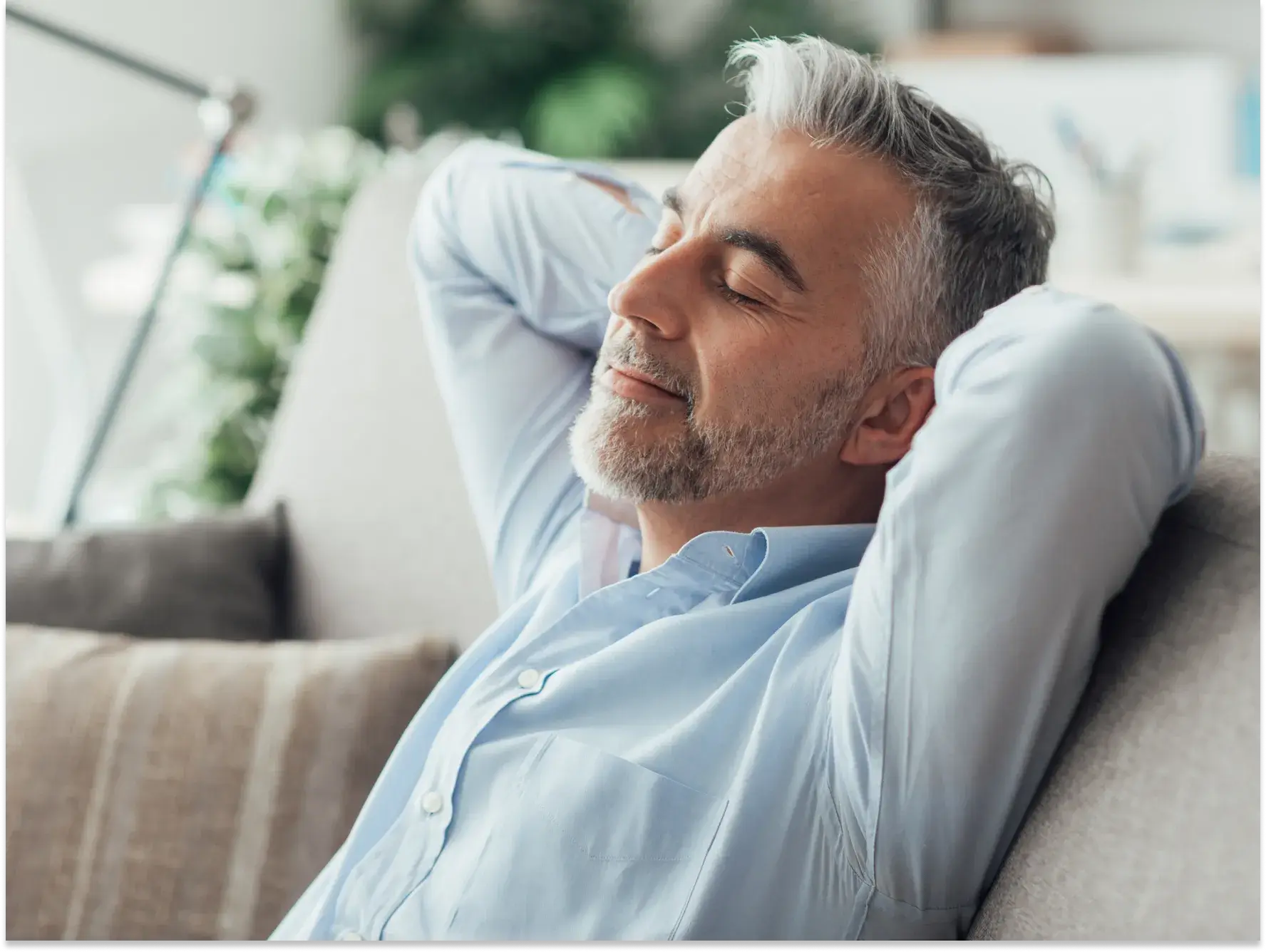 a man sitting on a couch with his hands behind his head