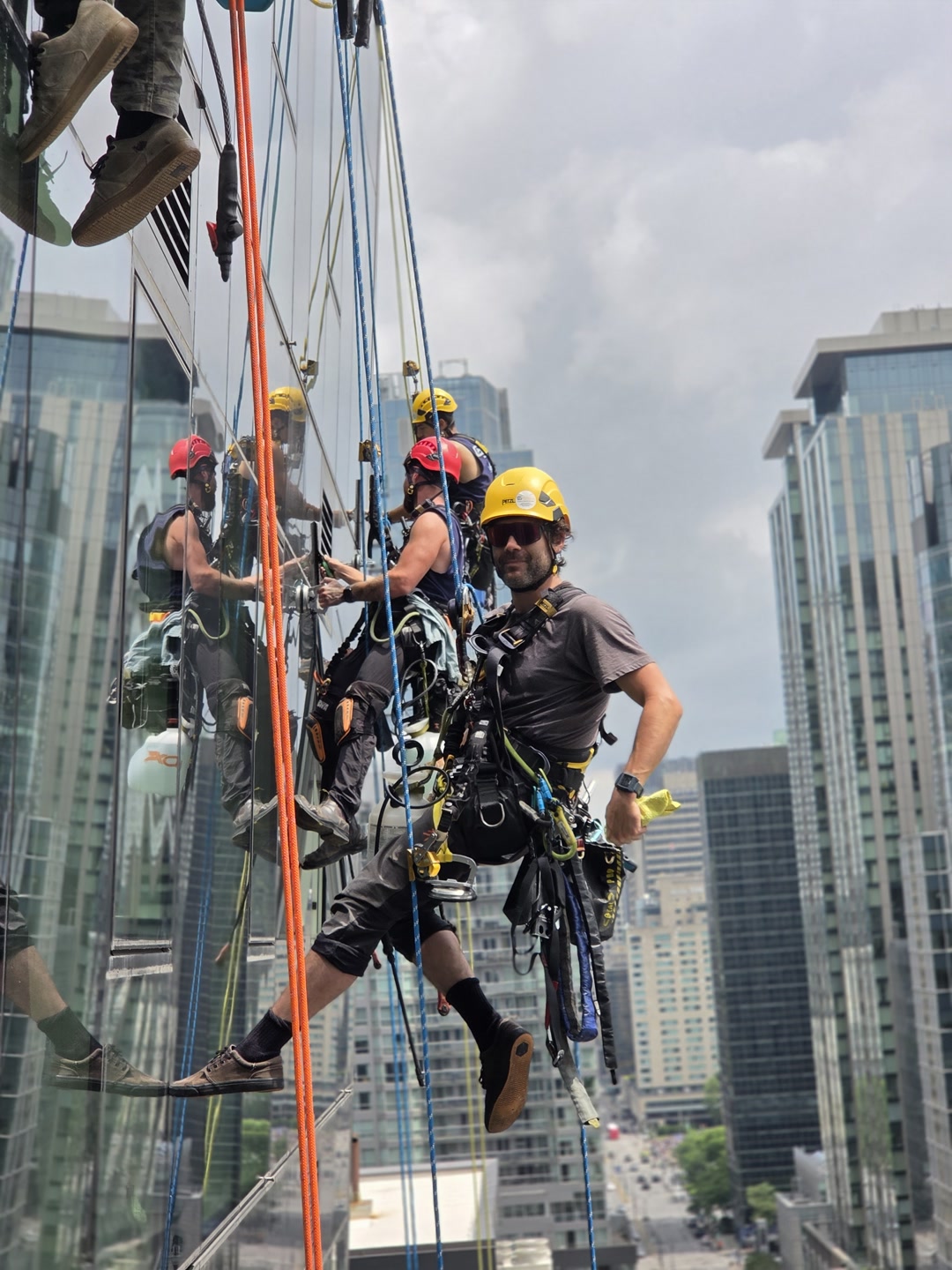 Professionnels du nettoyage de vitres suspendus par cordes sur un immeuble