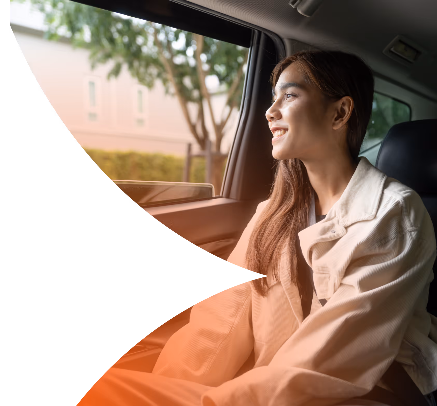 Woman in a beige jacket smiling and looking out of a car window during daytime.