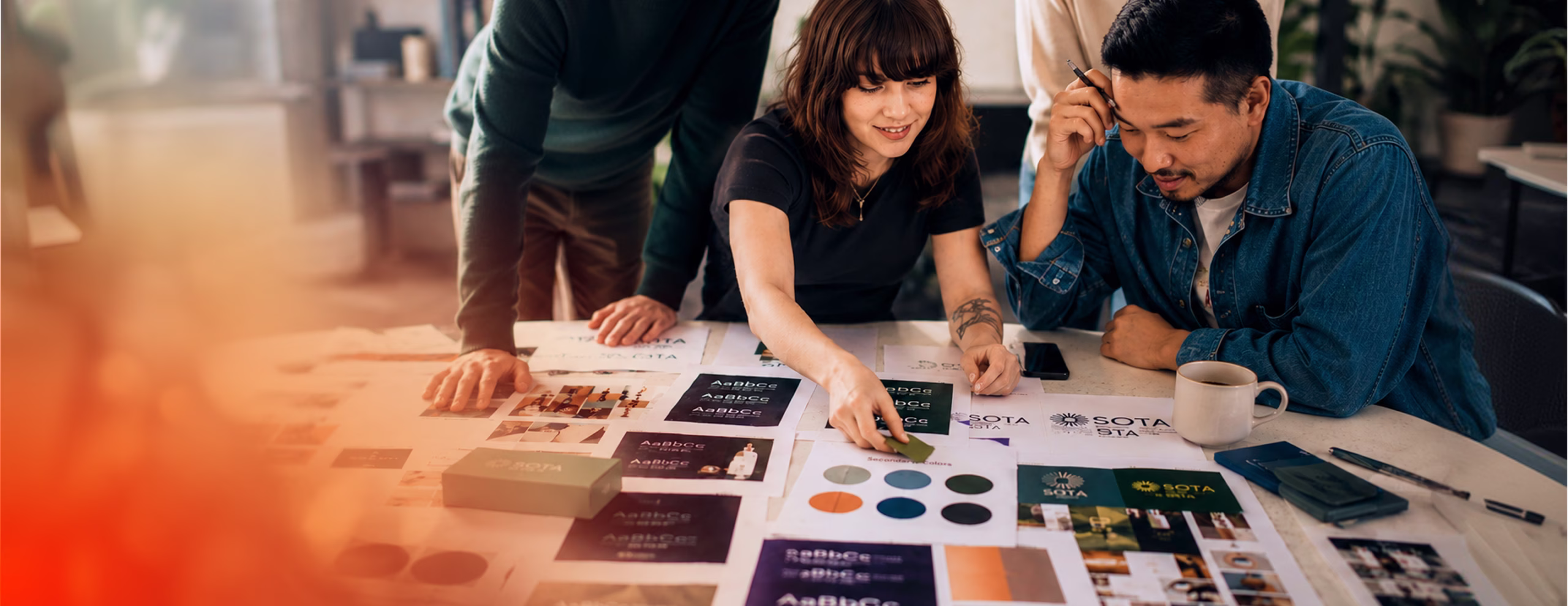 Three people reviewing printed color samples and branding materials around a table.