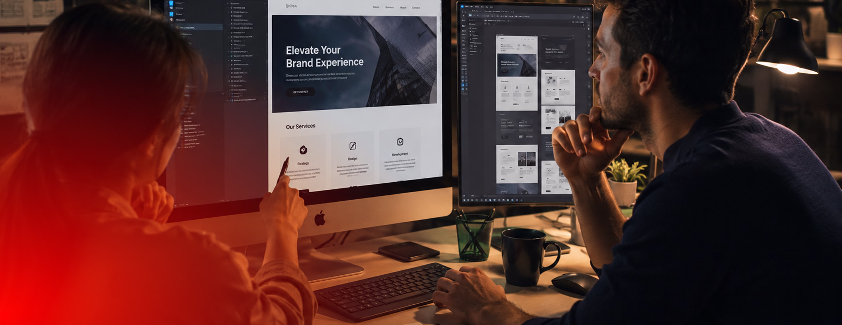 Two designers reviewing brand experience and website layouts on dual monitors in a dimly lit workspace.